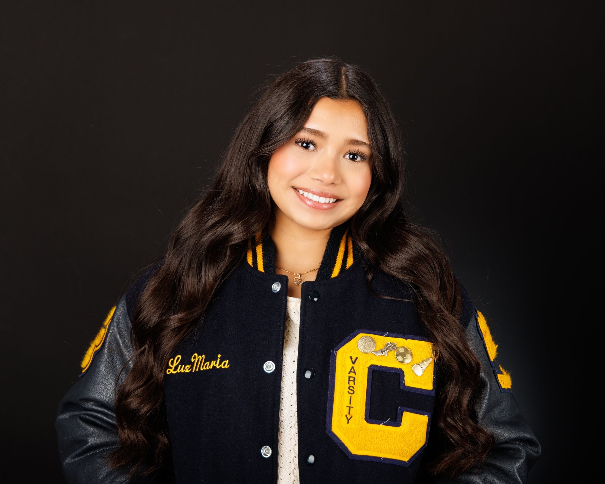 Maria in cream sweater with varsity jacket draped over shoulder