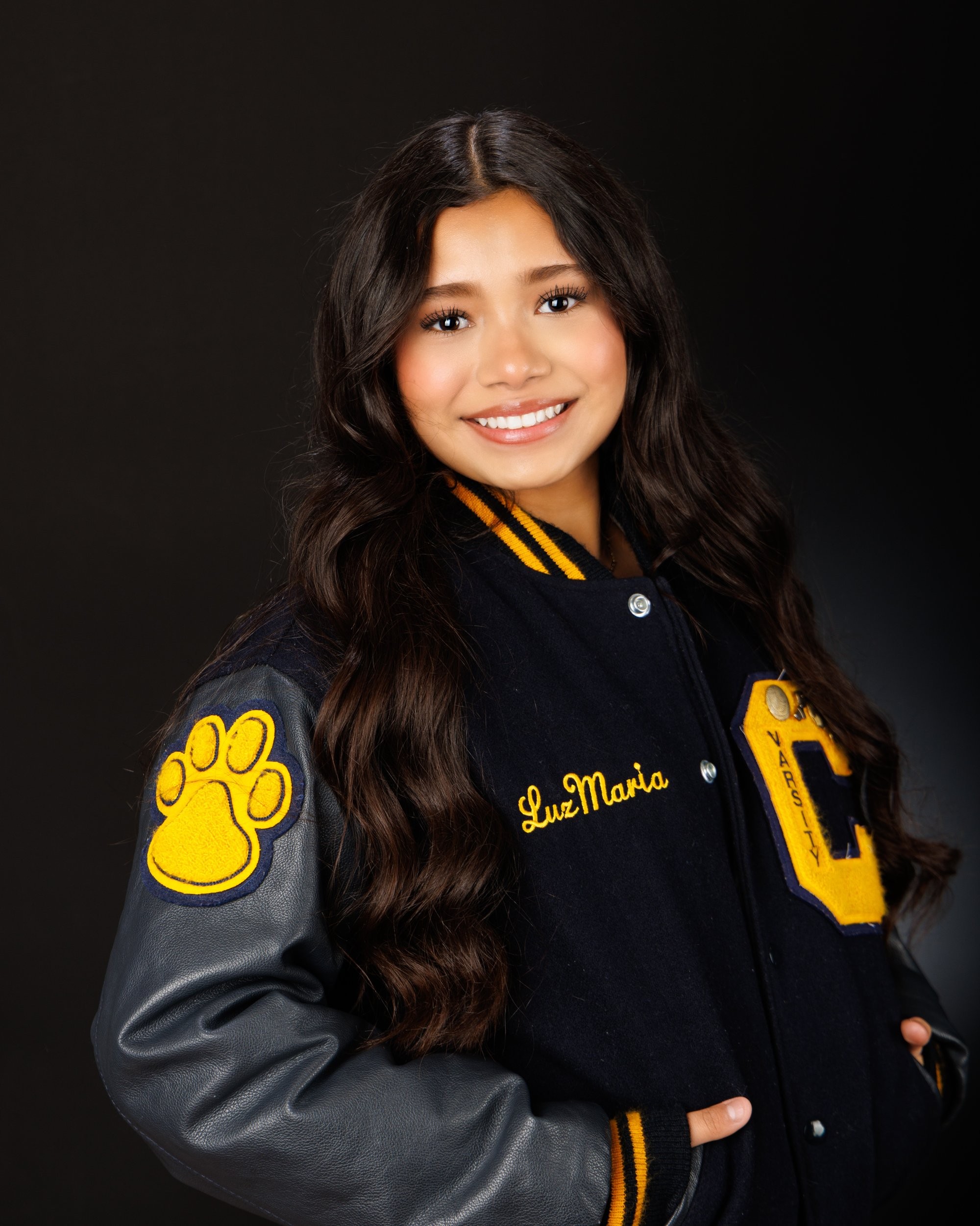 Maria in cream sweater with varsity jacket draped over shoulder