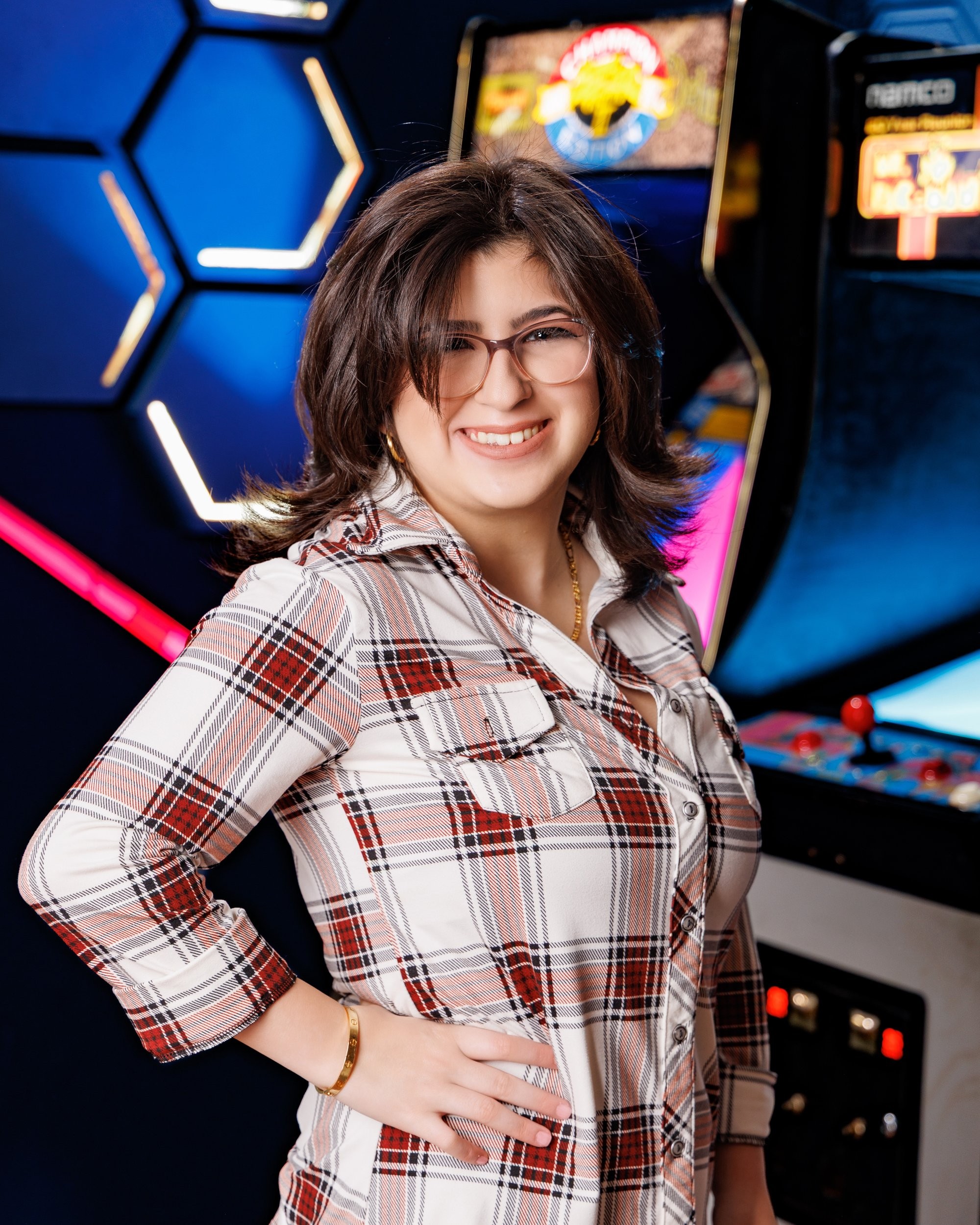 Woman posing confidently in front of an arcade game machine during a senior photo session