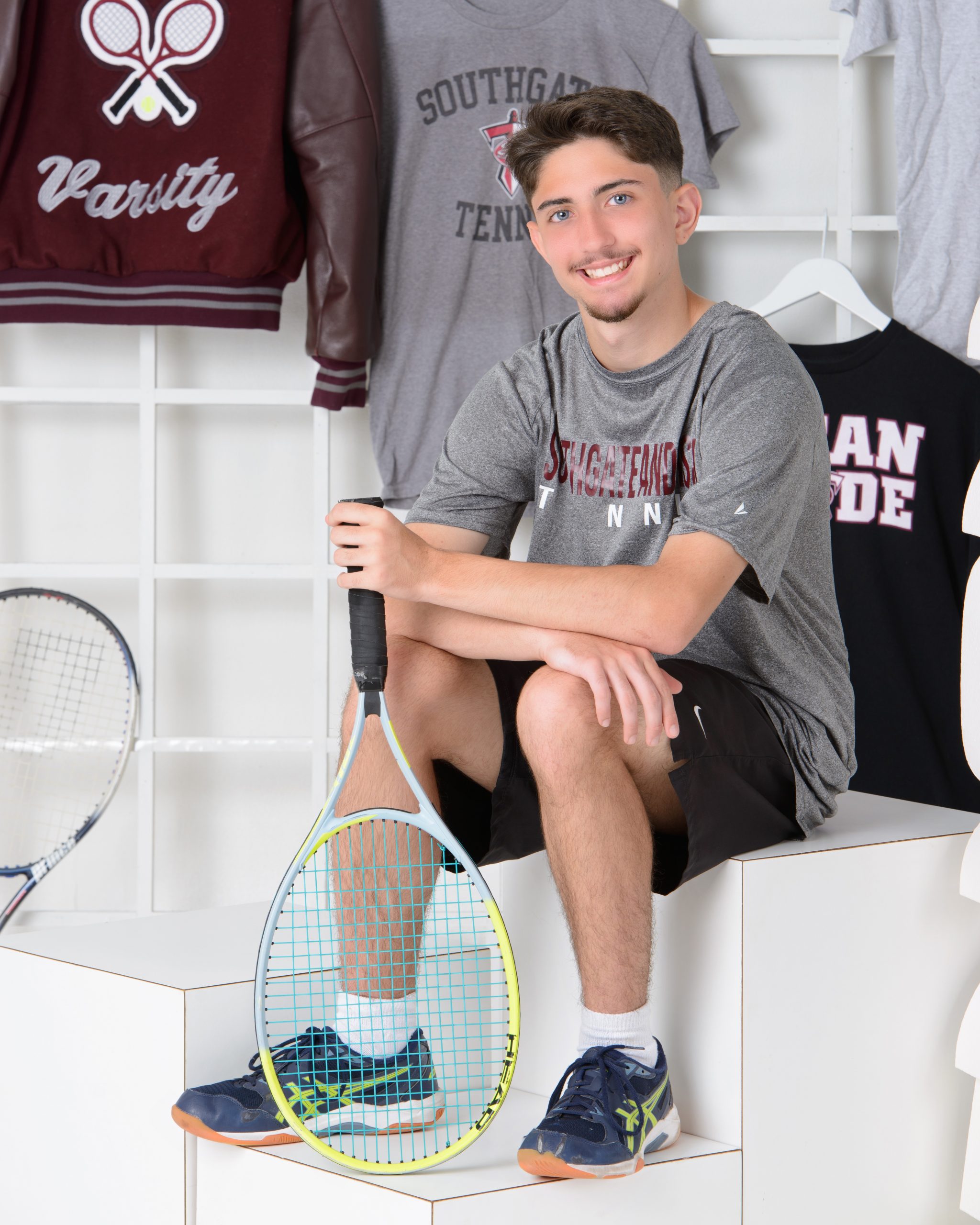 Sean posing with tennis equipment in Southgate Anderson sports attire