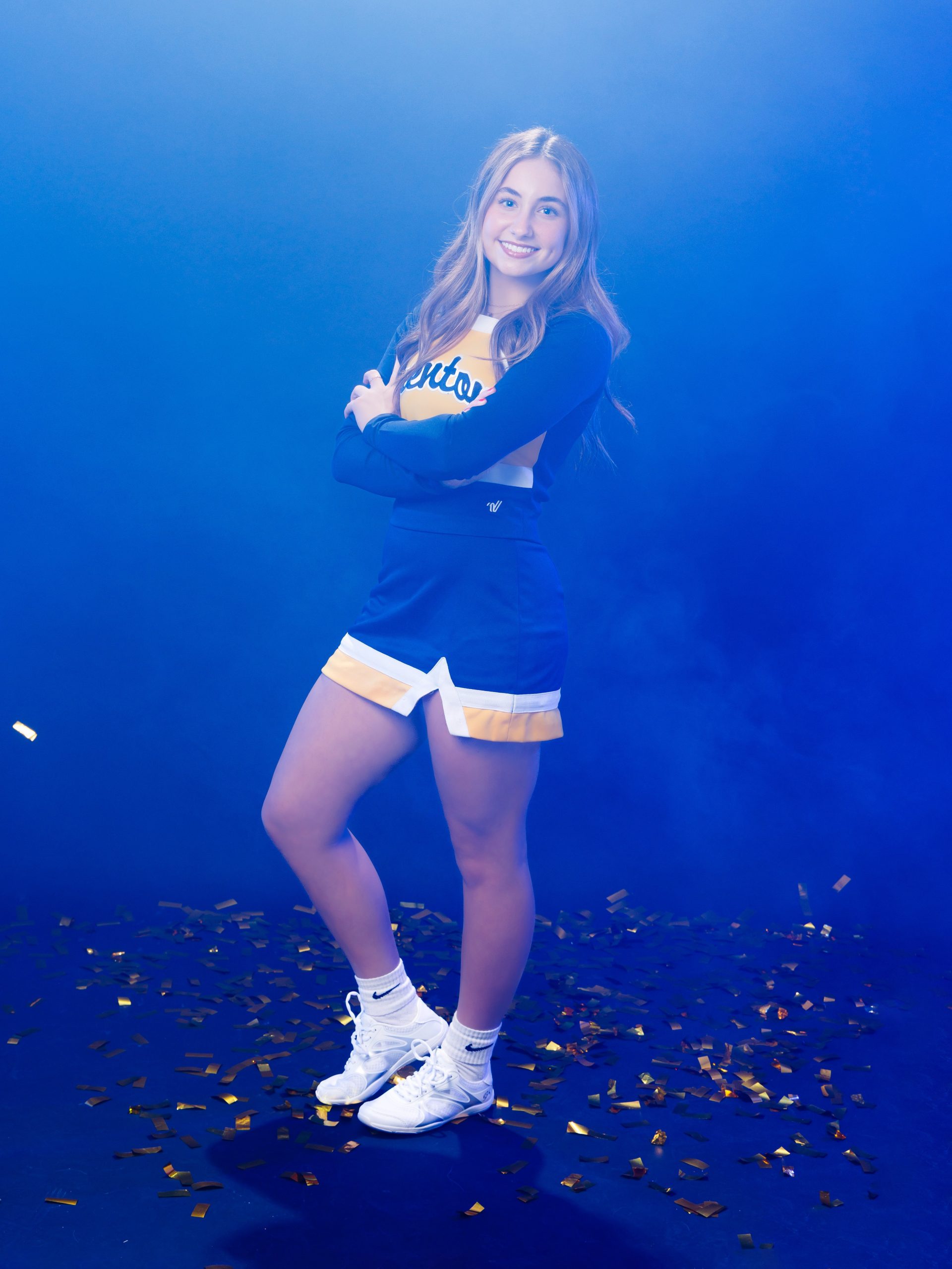 Cheerleader holding flames in hands wearing Trenton cheerleading outfit with confetti