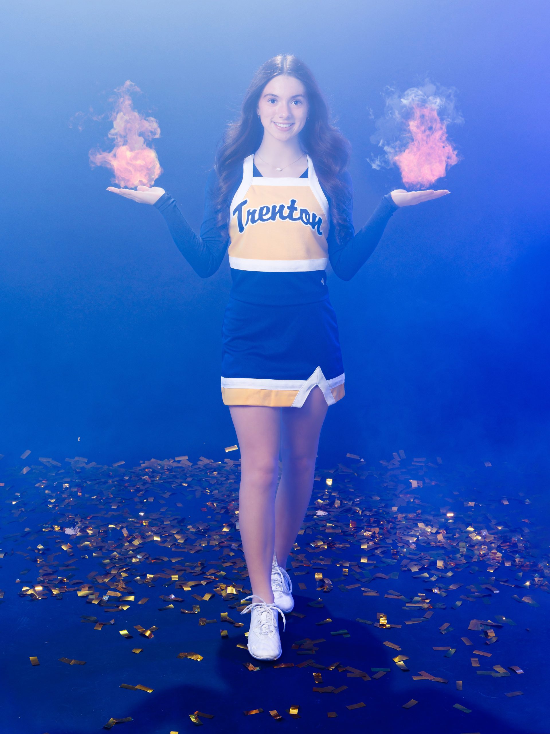 Cheerleader posing with hand on hip against blue backdrop with confetti