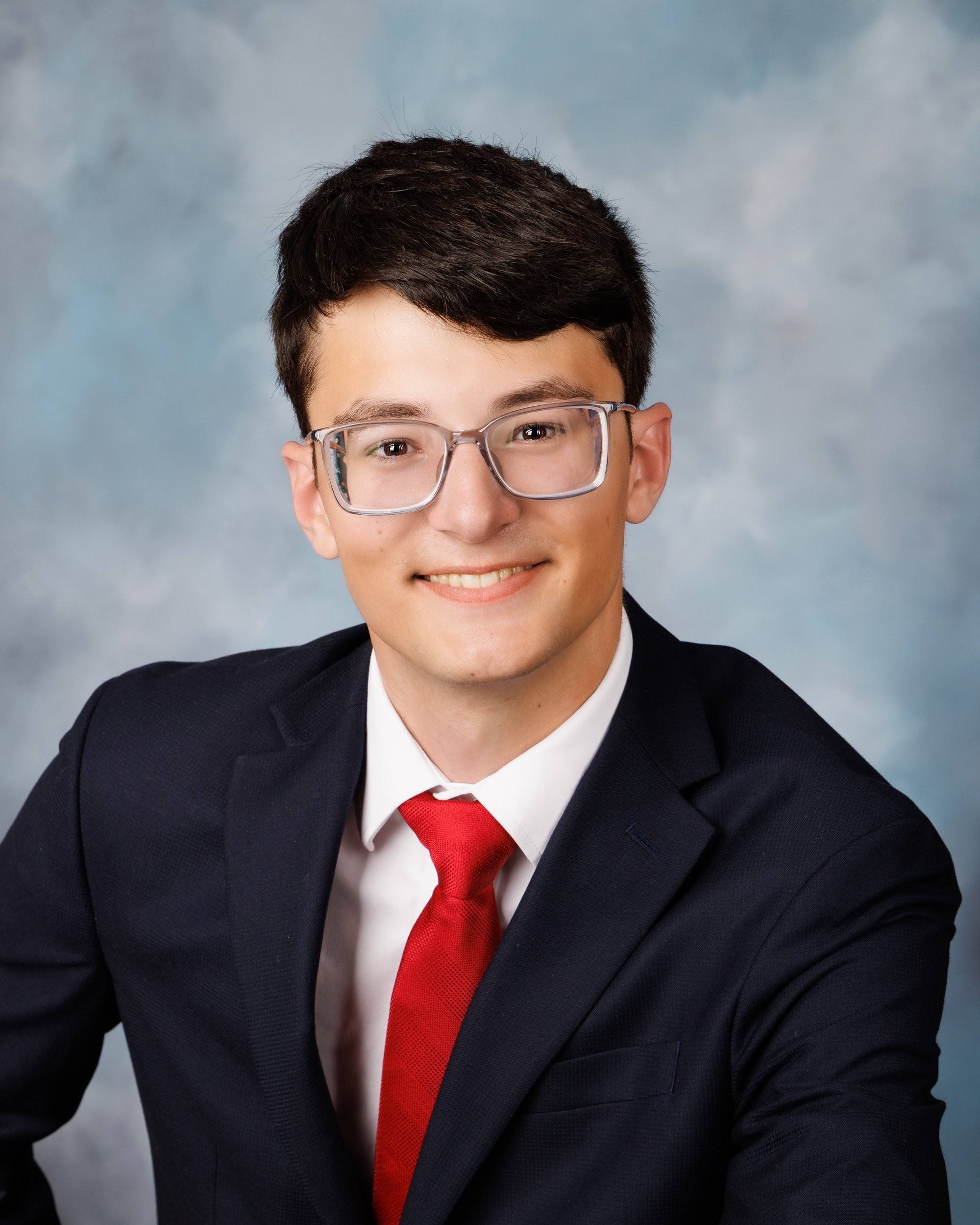Anthony in a navy suit, white shirt, and red tie for his Trenton senior photography session