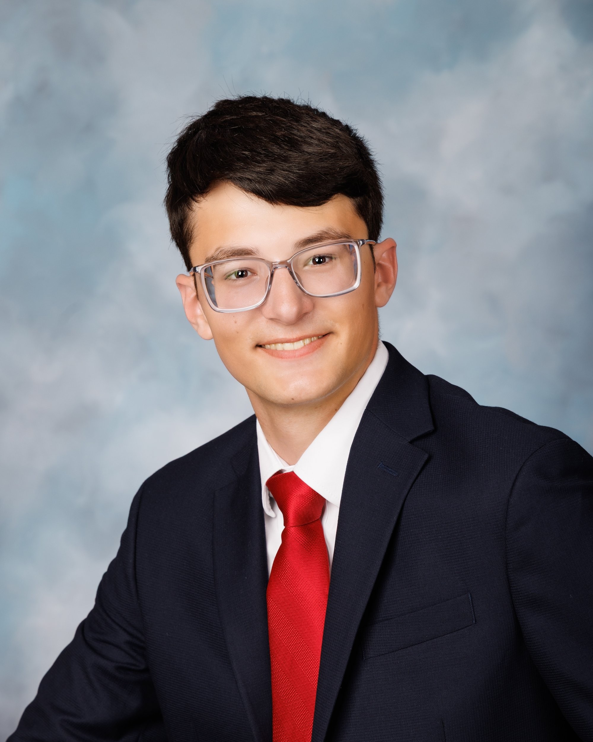 Anthony holding an American football while dressed in a navy suit and red tie for his Trenton senior portrait