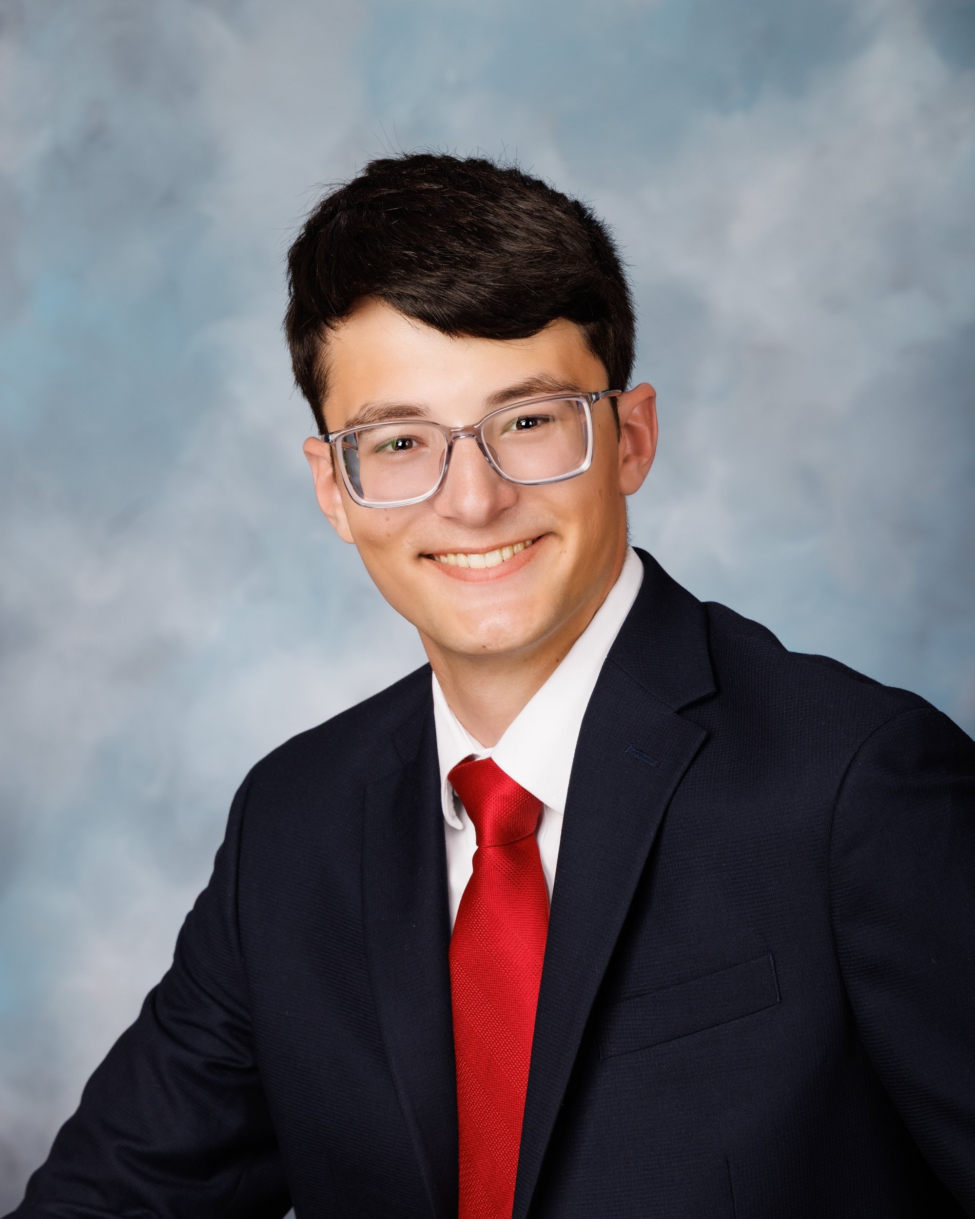 Anthony holding an American football while dressed in a navy suit and red tie for his Trenton senior portrait
