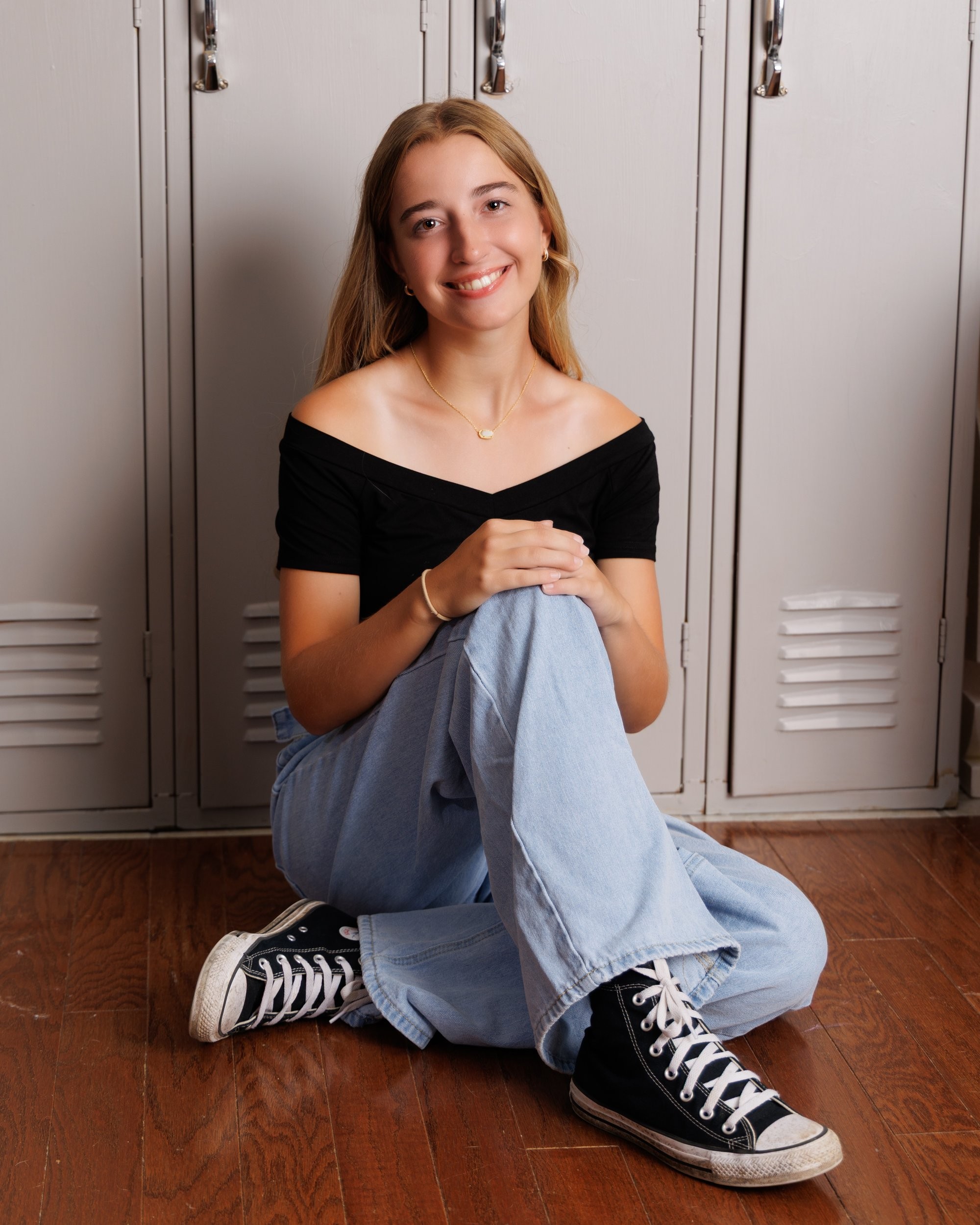Professional senior headshot of Anika with long hair, smiling against a soft blue backdrop