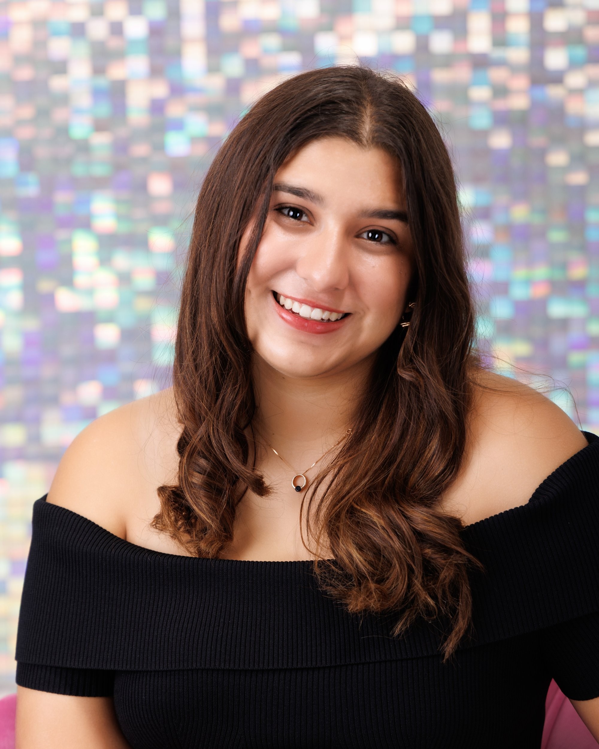 Back view of Ava holding a soccer ball in Trenton senior photo session, off-shoulder black top and mosaic wall