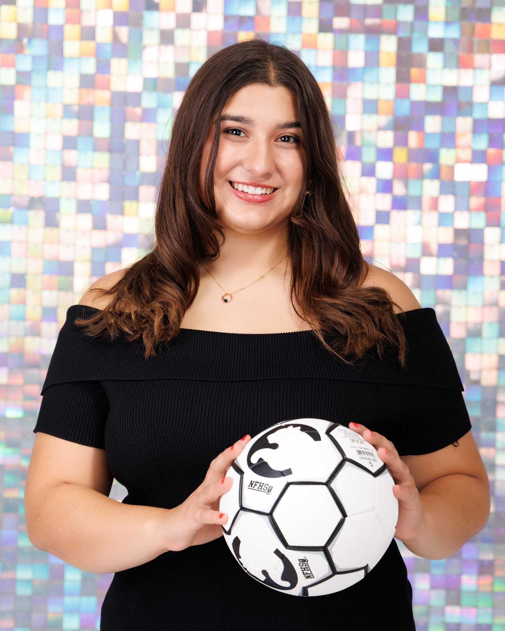 Back view of Ava holding a soccer ball in Trenton senior photo session, off-shoulder black top and mosaic wall