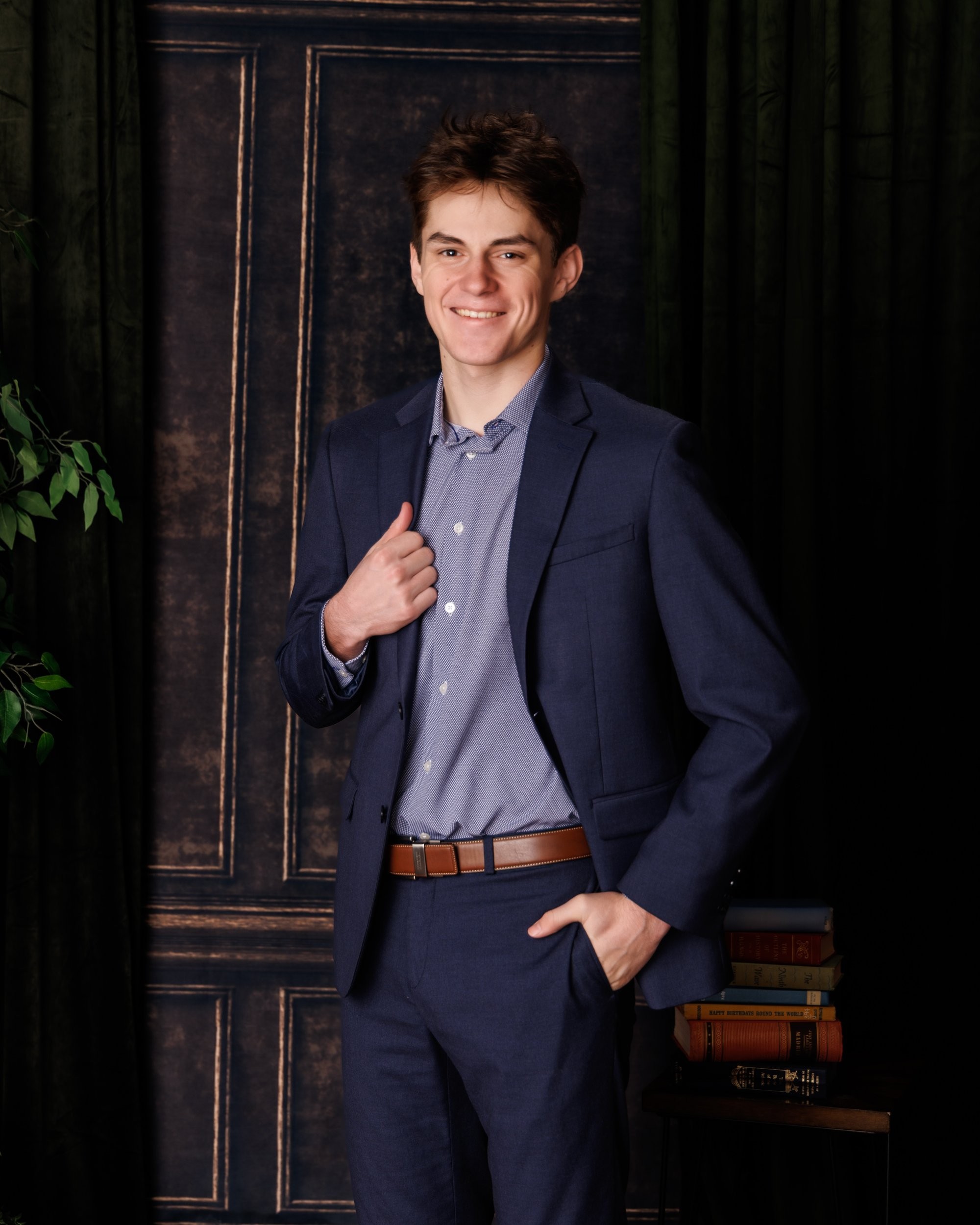 Casual Trenton senior portrait of a student seated on a black chair before a weathered white door