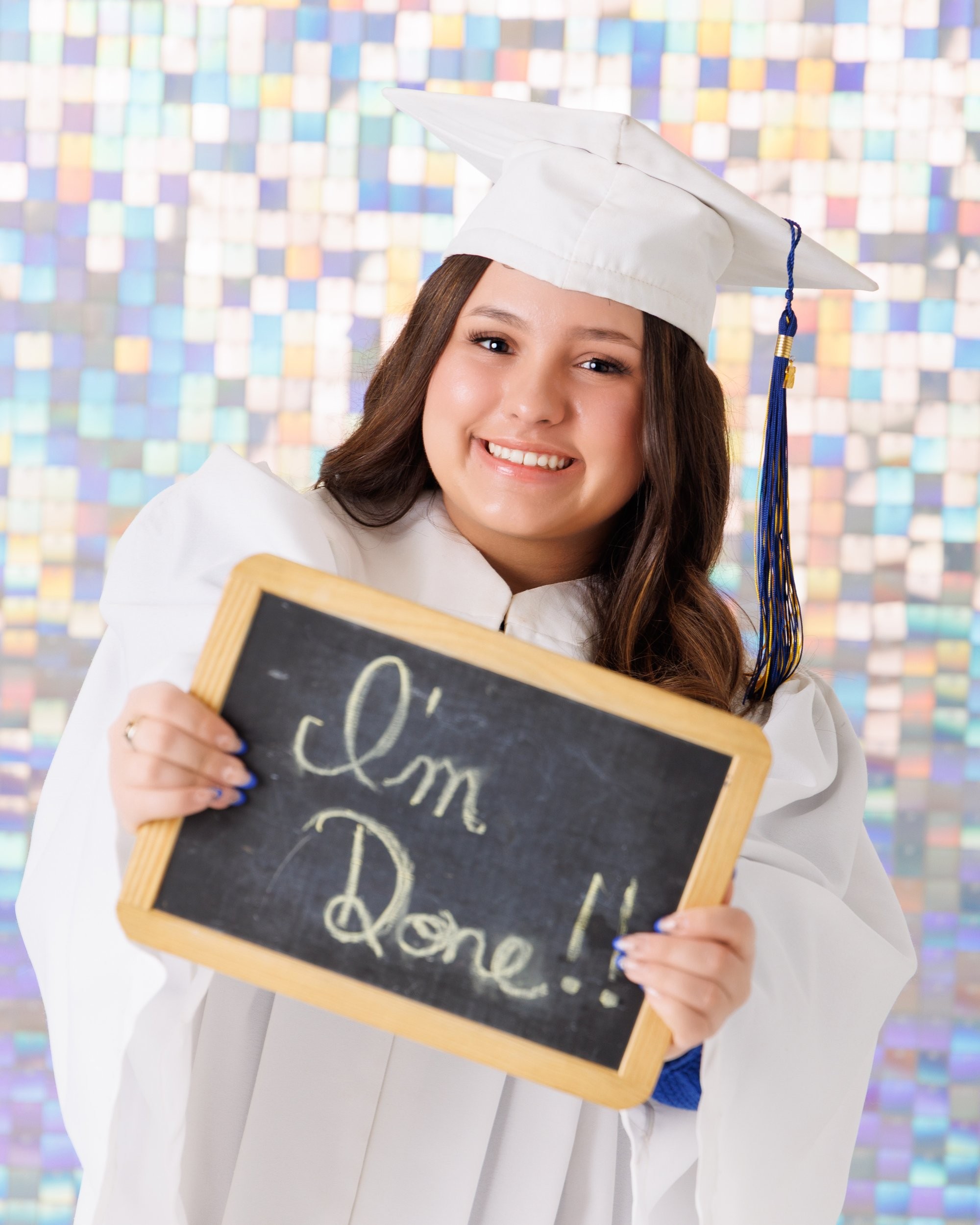Senior graduate in cap and gown holding blue and gold pom-poms against a solid blue background