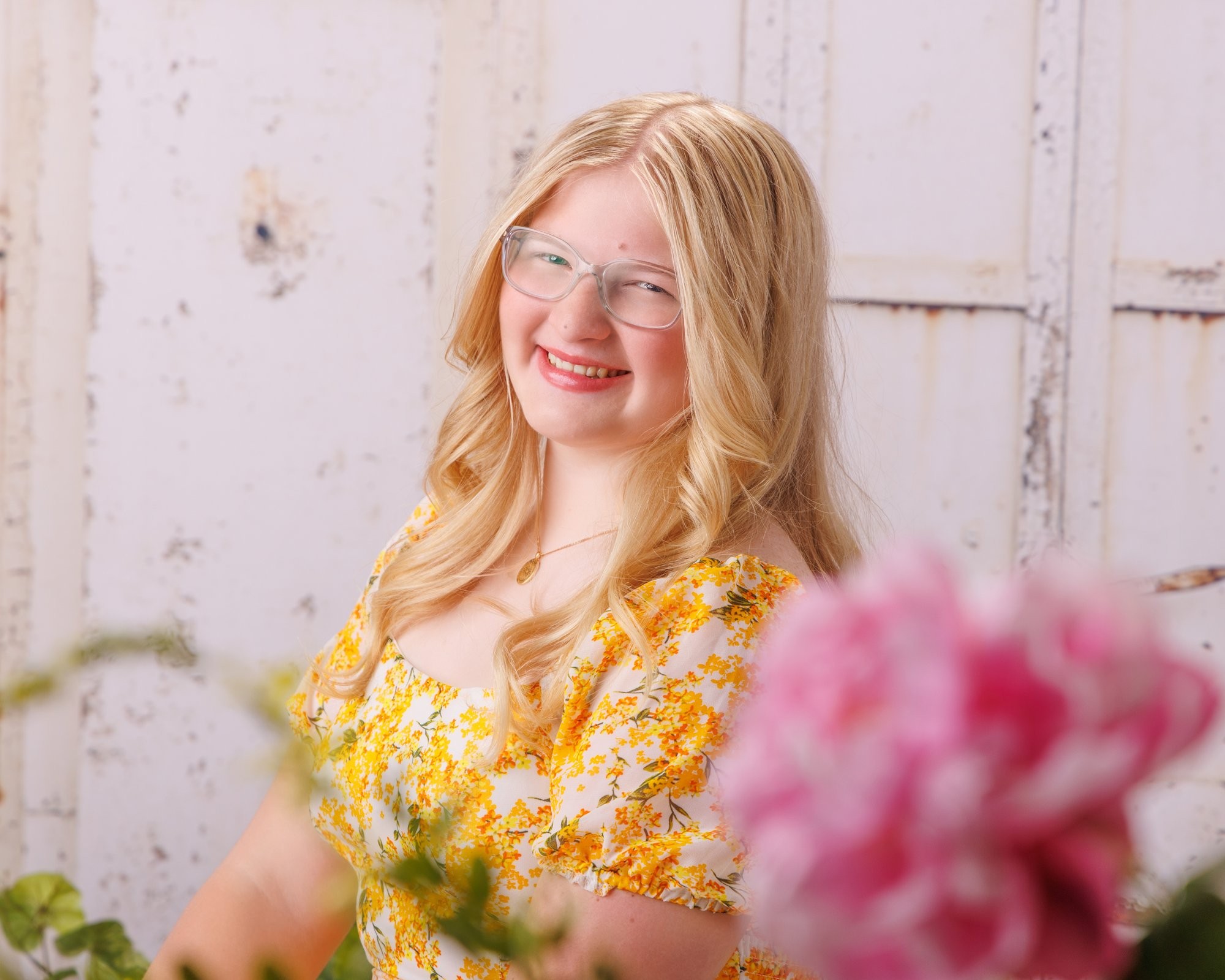 Elizabeth standing in a yellow floral dress near white doors, walking pose with flower arrangements