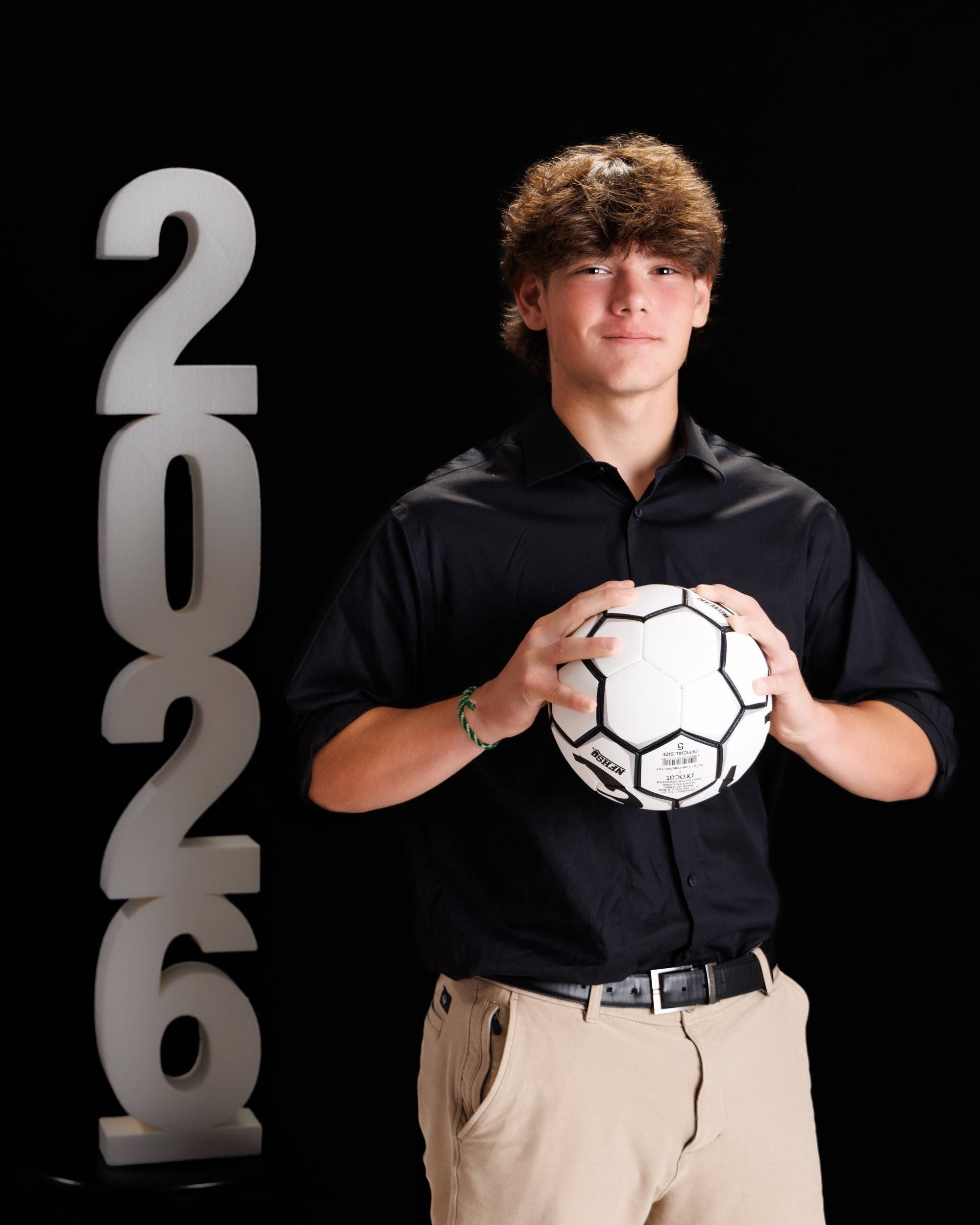 Trenton Senior Portrait - Jacob holding soccer ball in black shirt and khaki pants