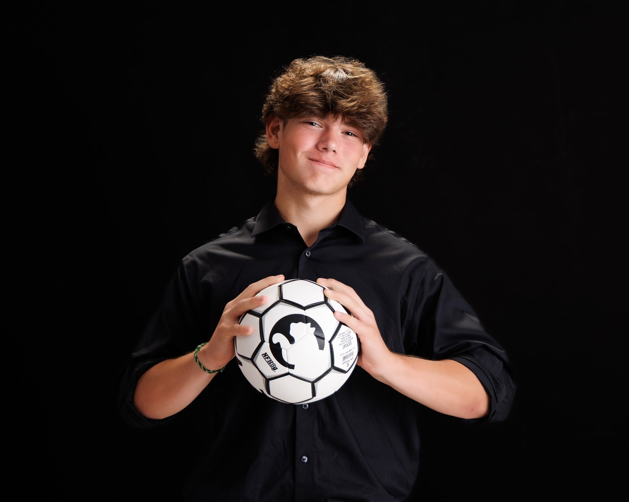 Trenton Senior Portrait - Jacob holding soccer ball in black shirt and khaki pants