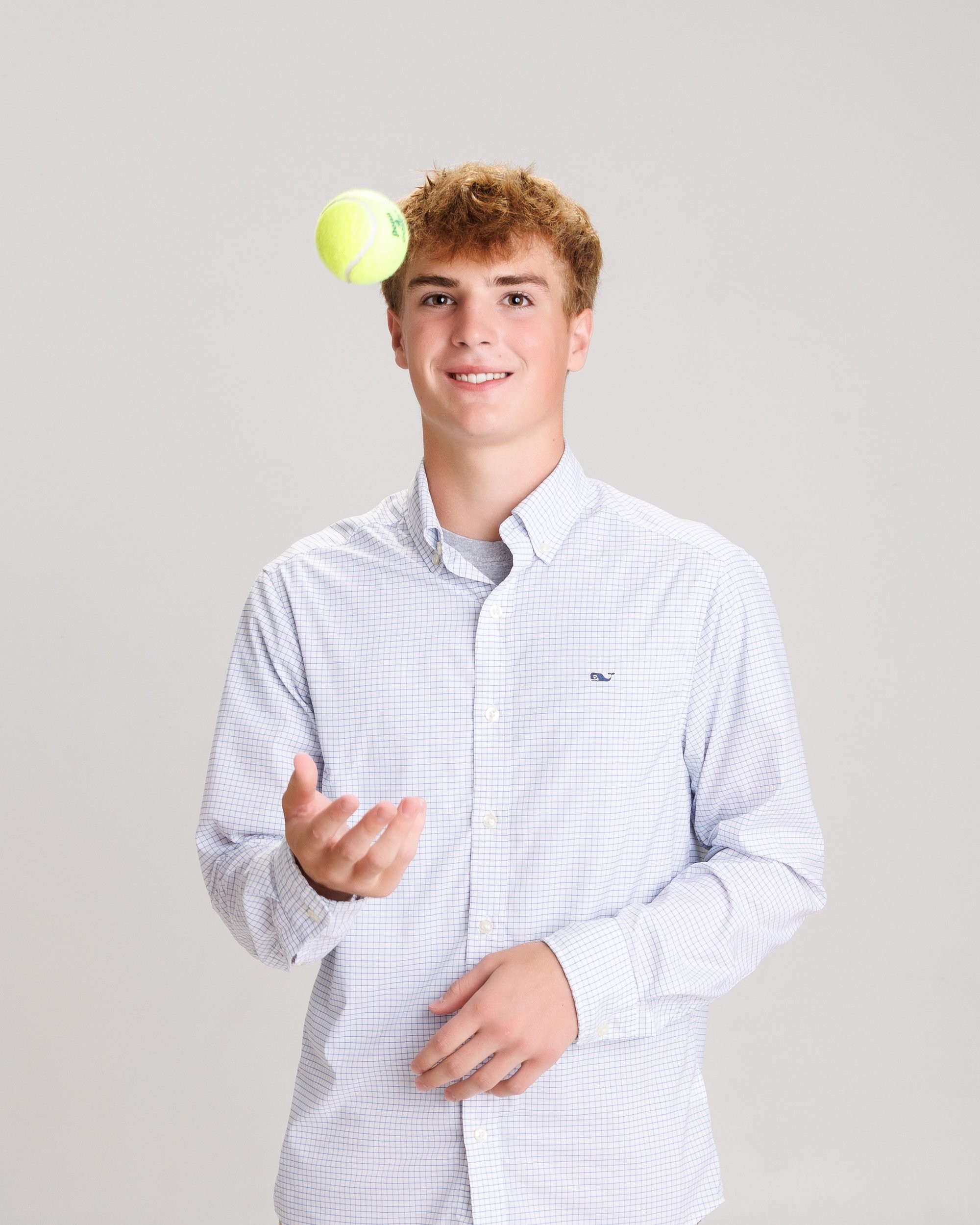 Jaxon juggling a tennis ball in a light blue checkered shirt, Trenton senior portraits