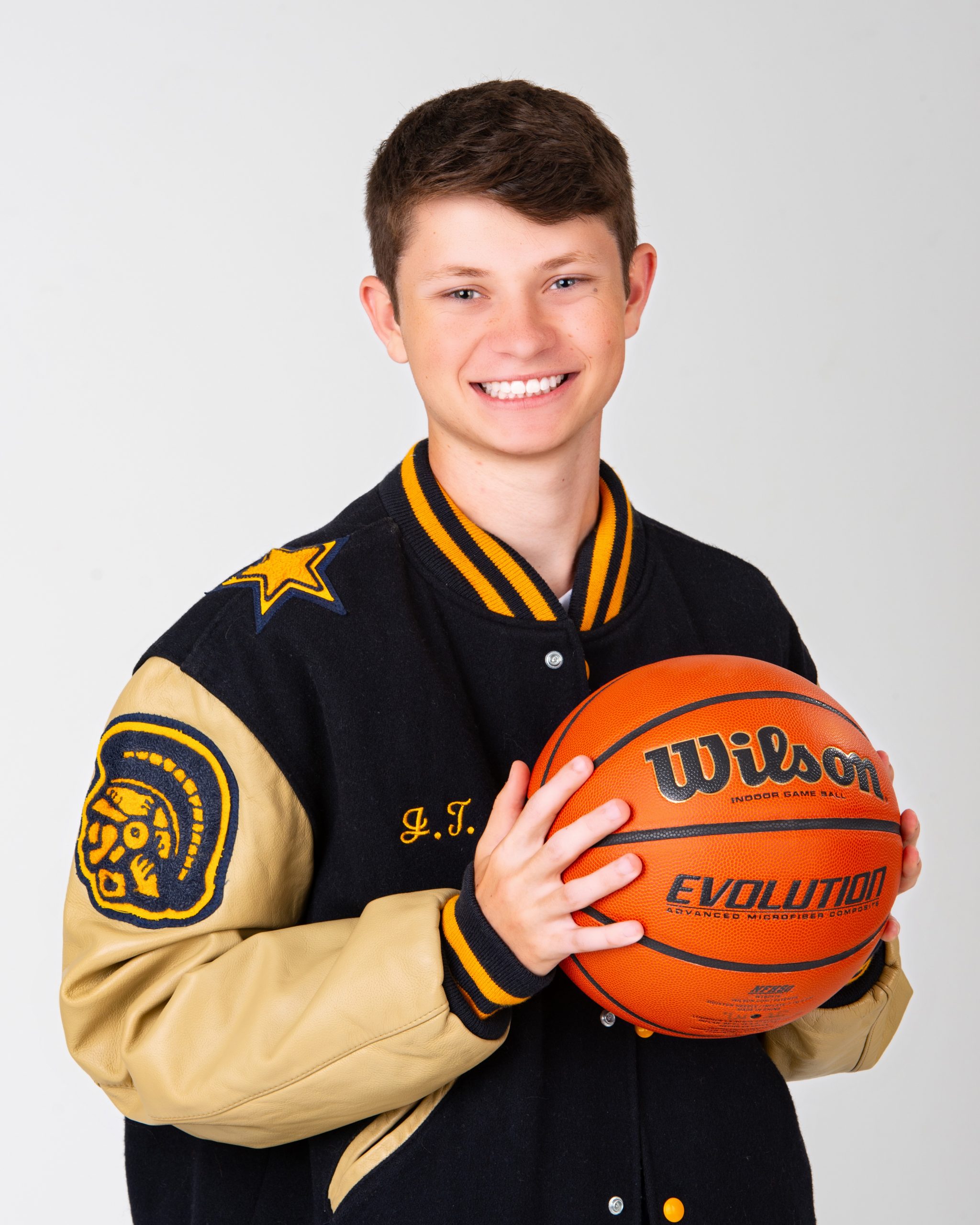 Trenton Varsity jacket with soccer and basketball graphics held by senior student-athlete