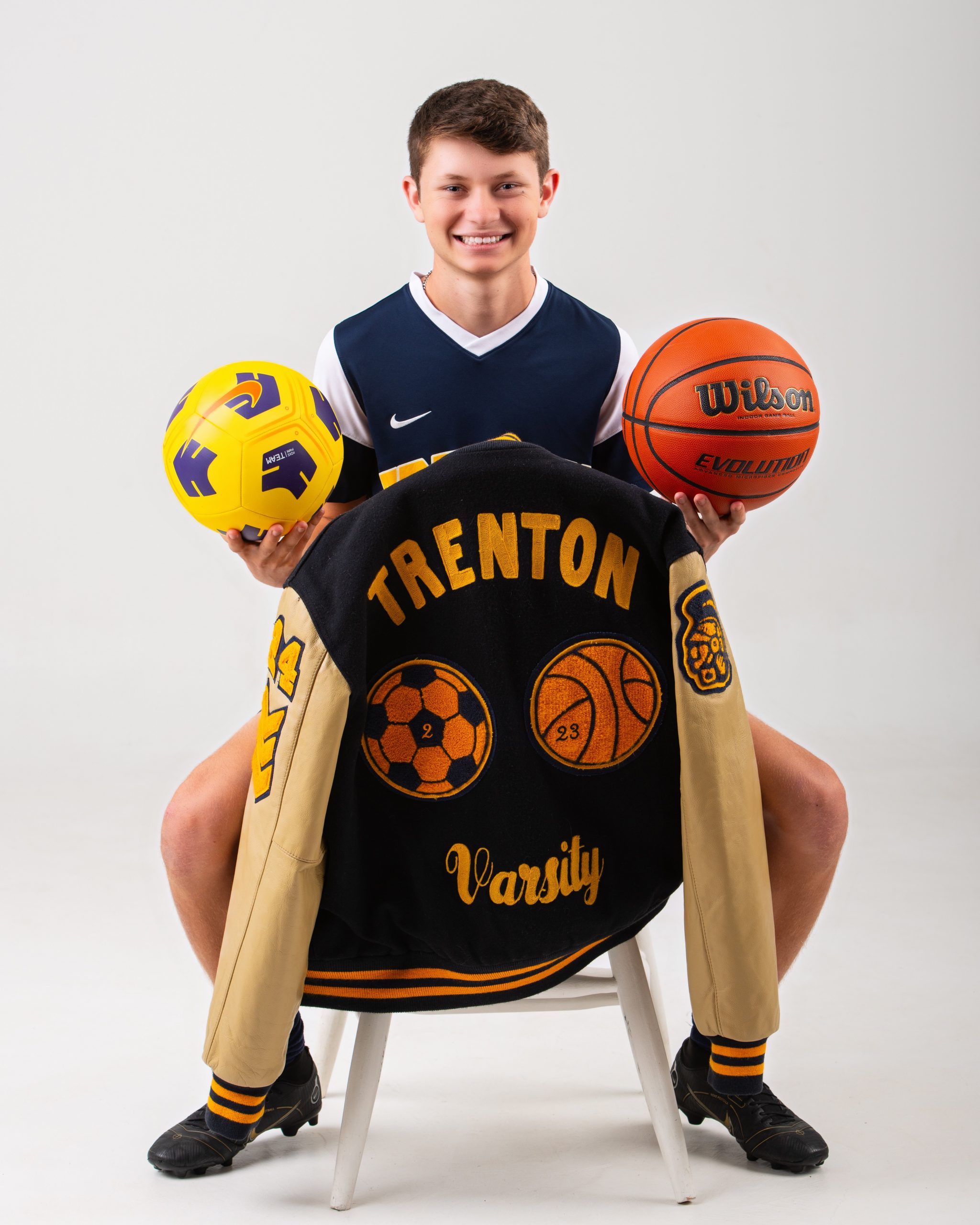 Trenton Varsity jacket with soccer and basketball graphics held by senior student-athlete