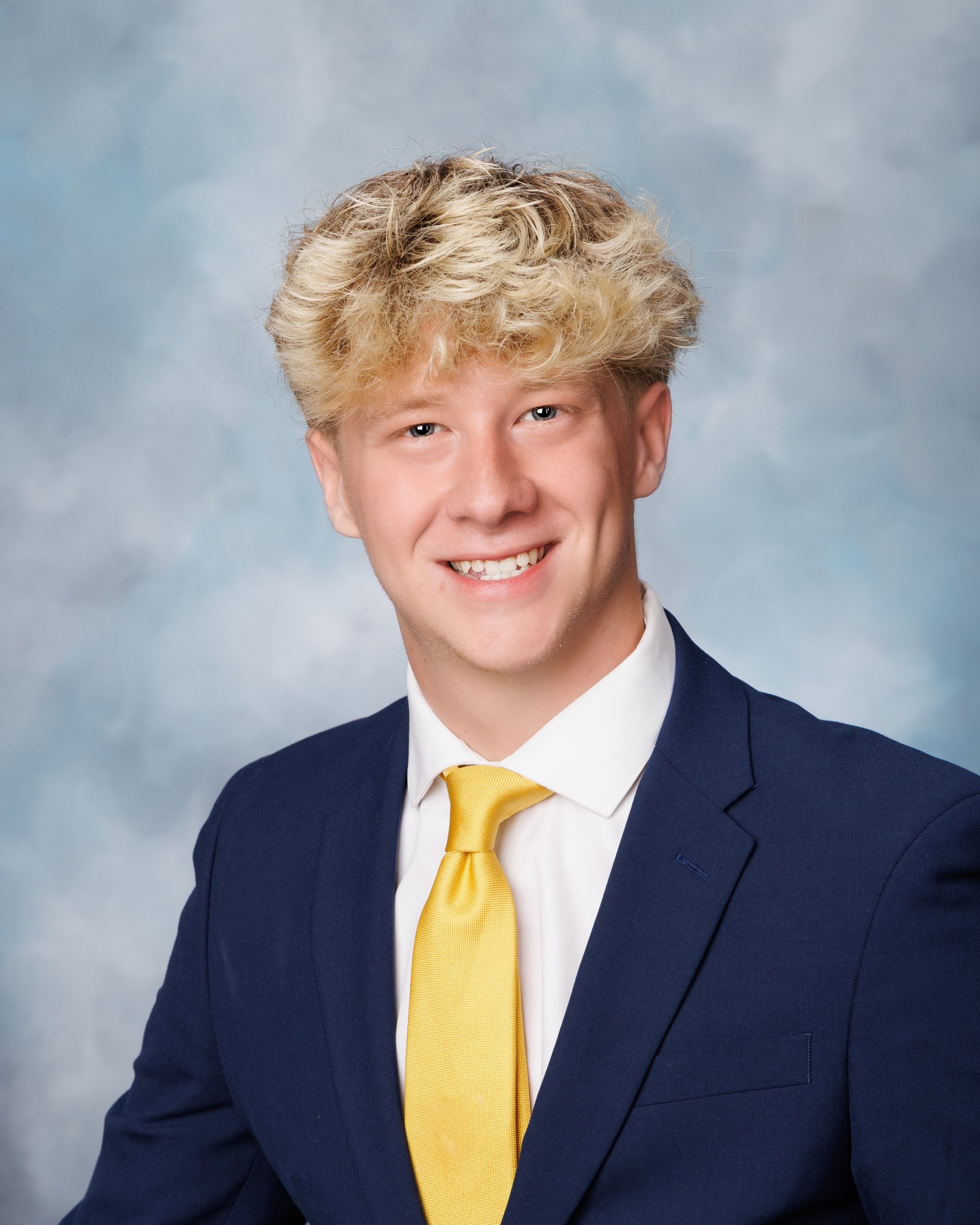 Trenton Senior Landon holding hockey stick and puck with '2026' backdrop