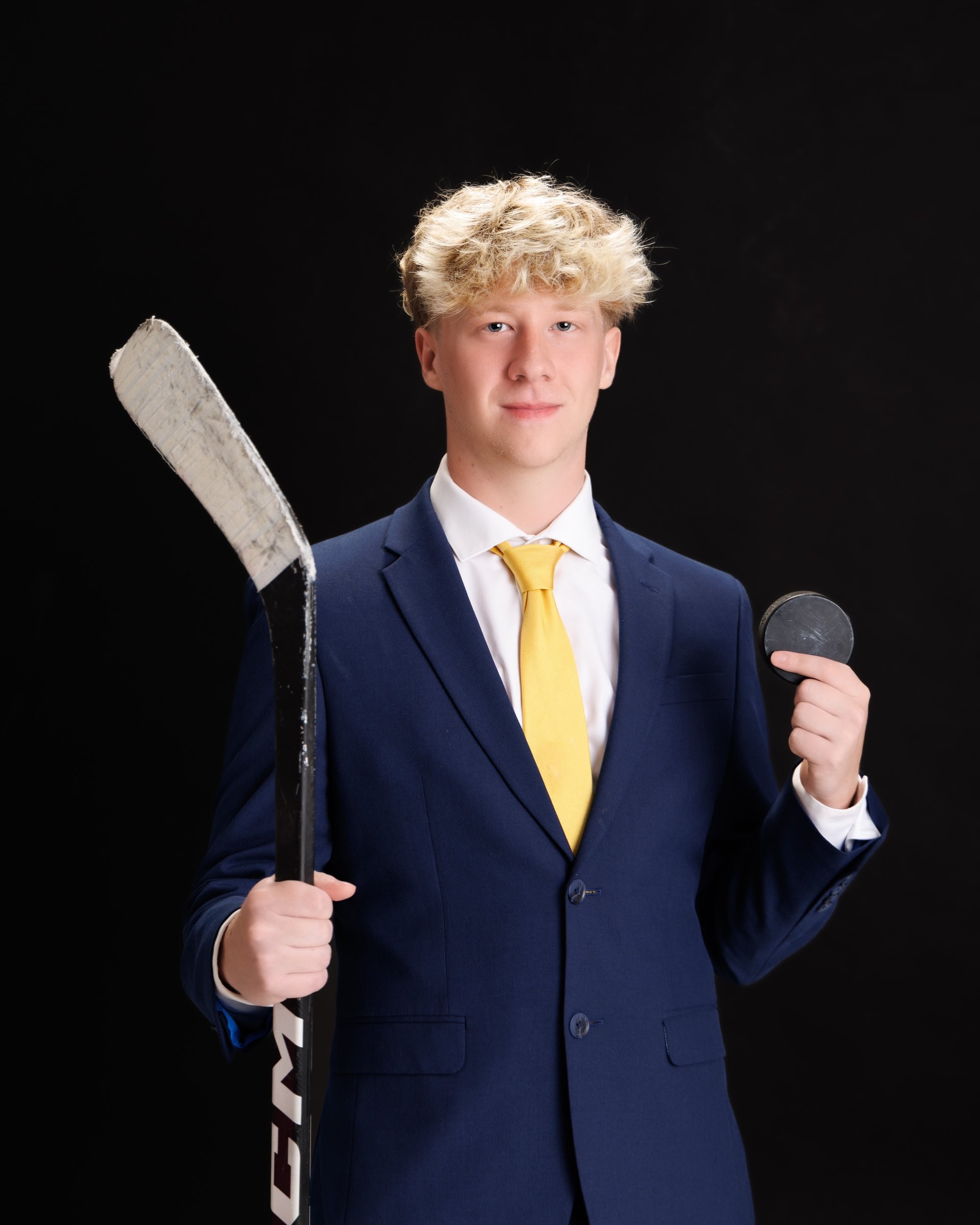 Trenton Senior Landon holding hockey stick and puck with '2026' backdrop