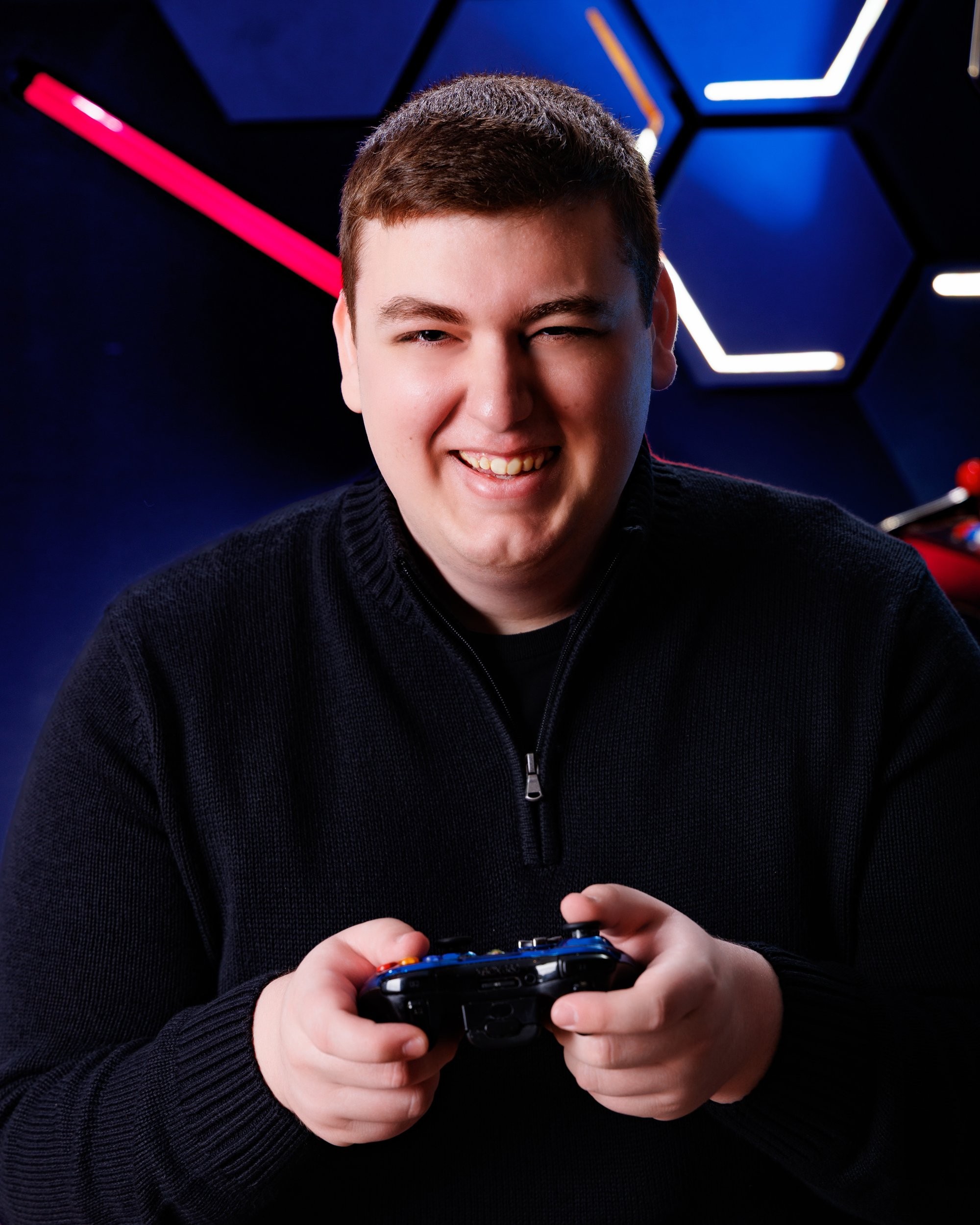 Matthew holding a game controller in a modern neon-lit studio environment