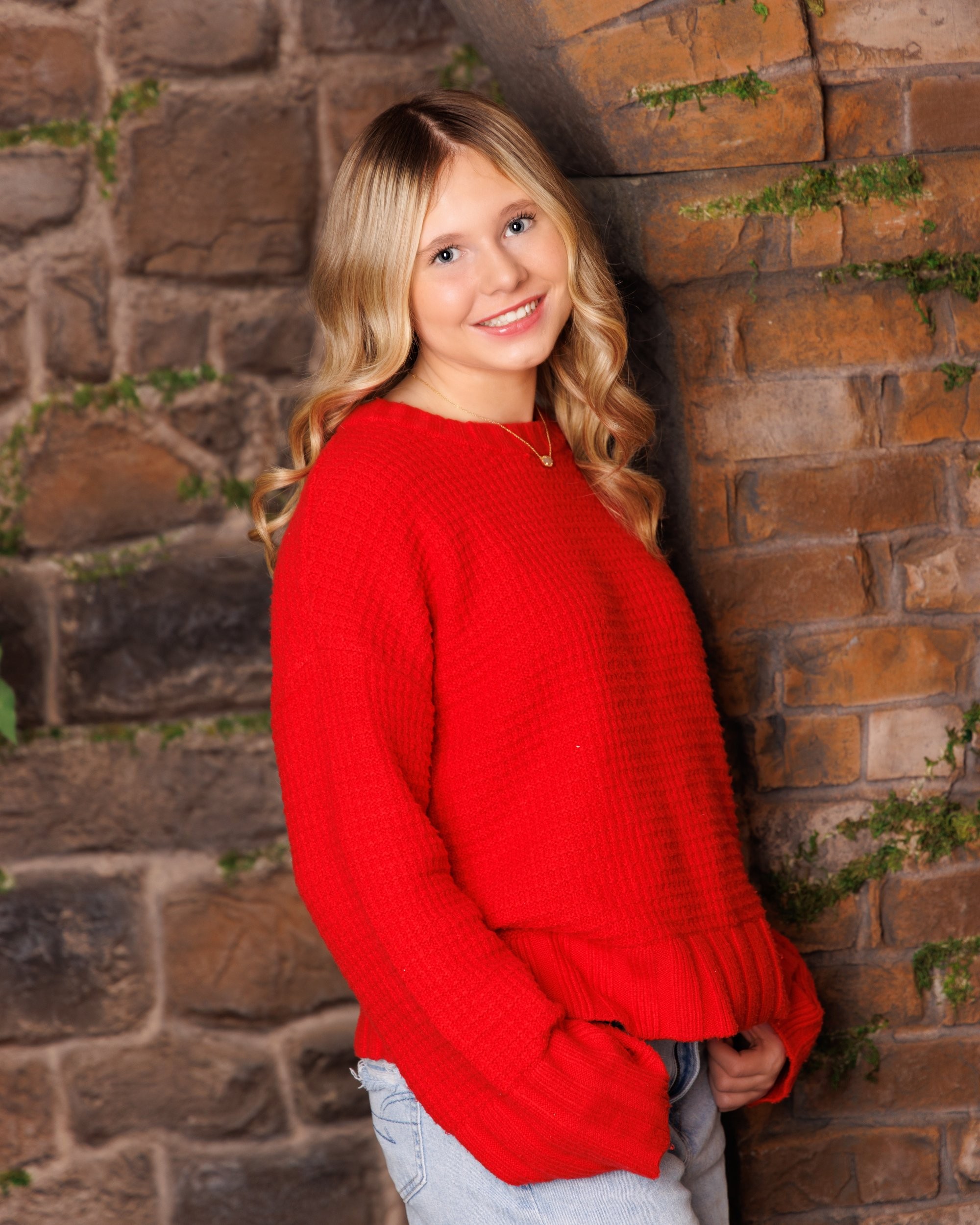 Trenton senior graduate McKenzie in a pink graduation gown with a 2023 tassel, smiling against a rustic backdrop