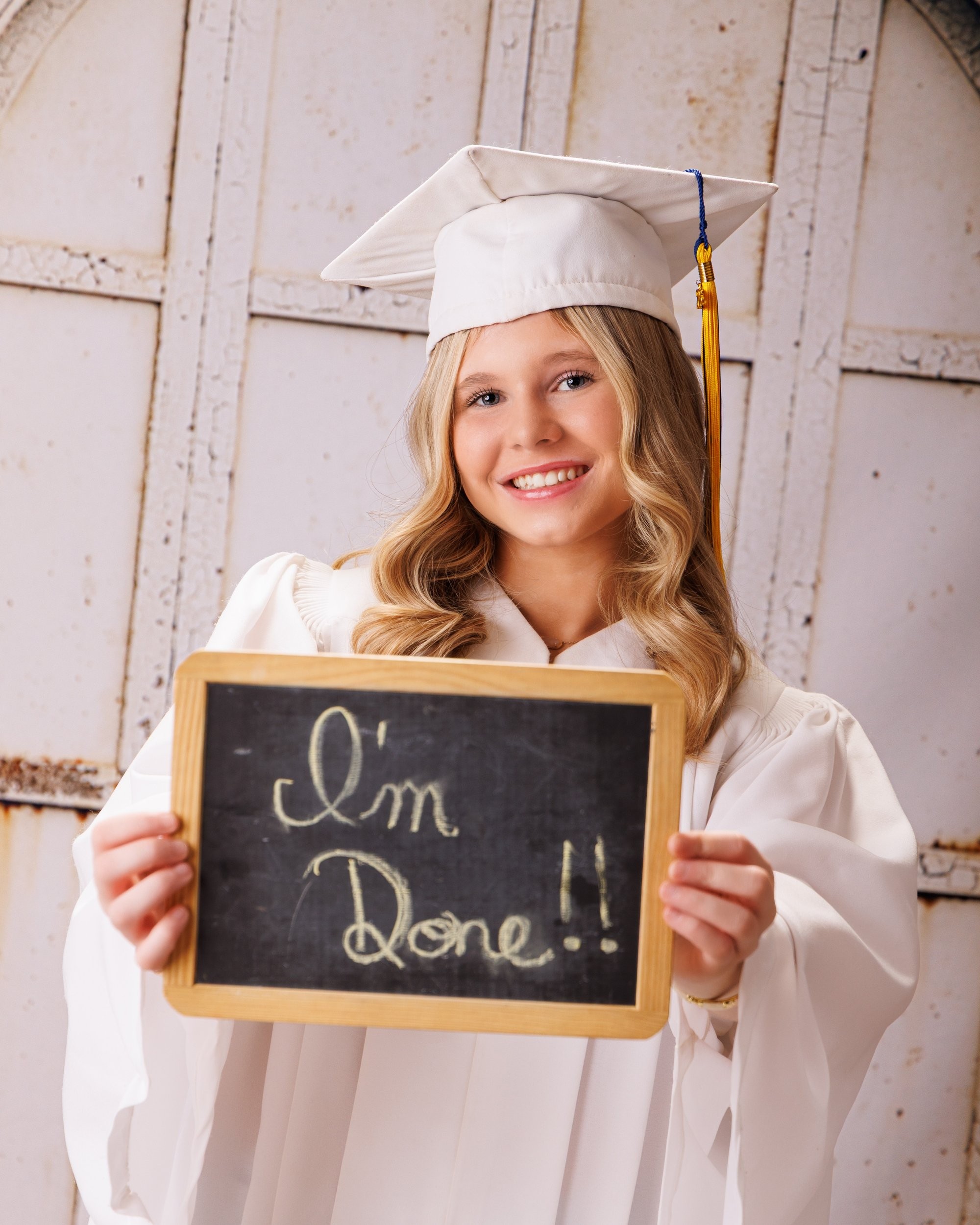 Trenton senior graduate McKenzie in a pink graduation gown with a 2023 tassel, smiling against a rustic backdrop