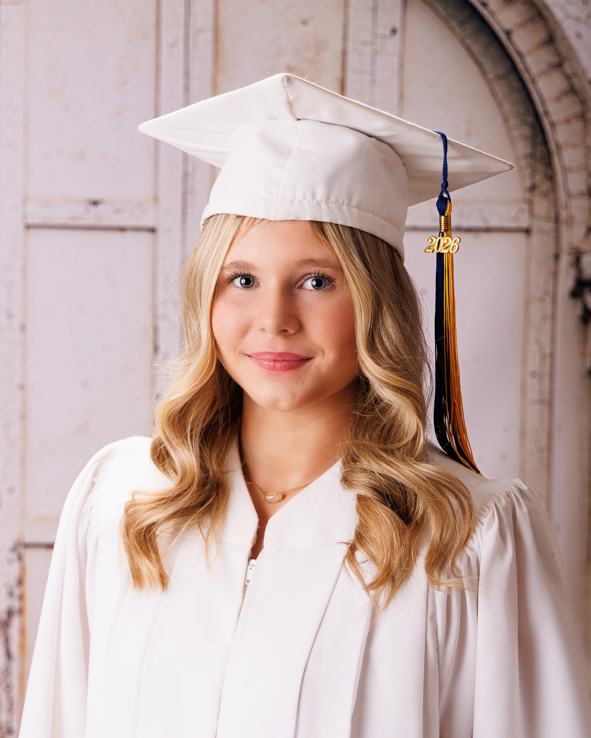 Trenton senior graduate McKenzie in a pink graduation gown with a 2023 tassel, smiling against a rustic backdrop