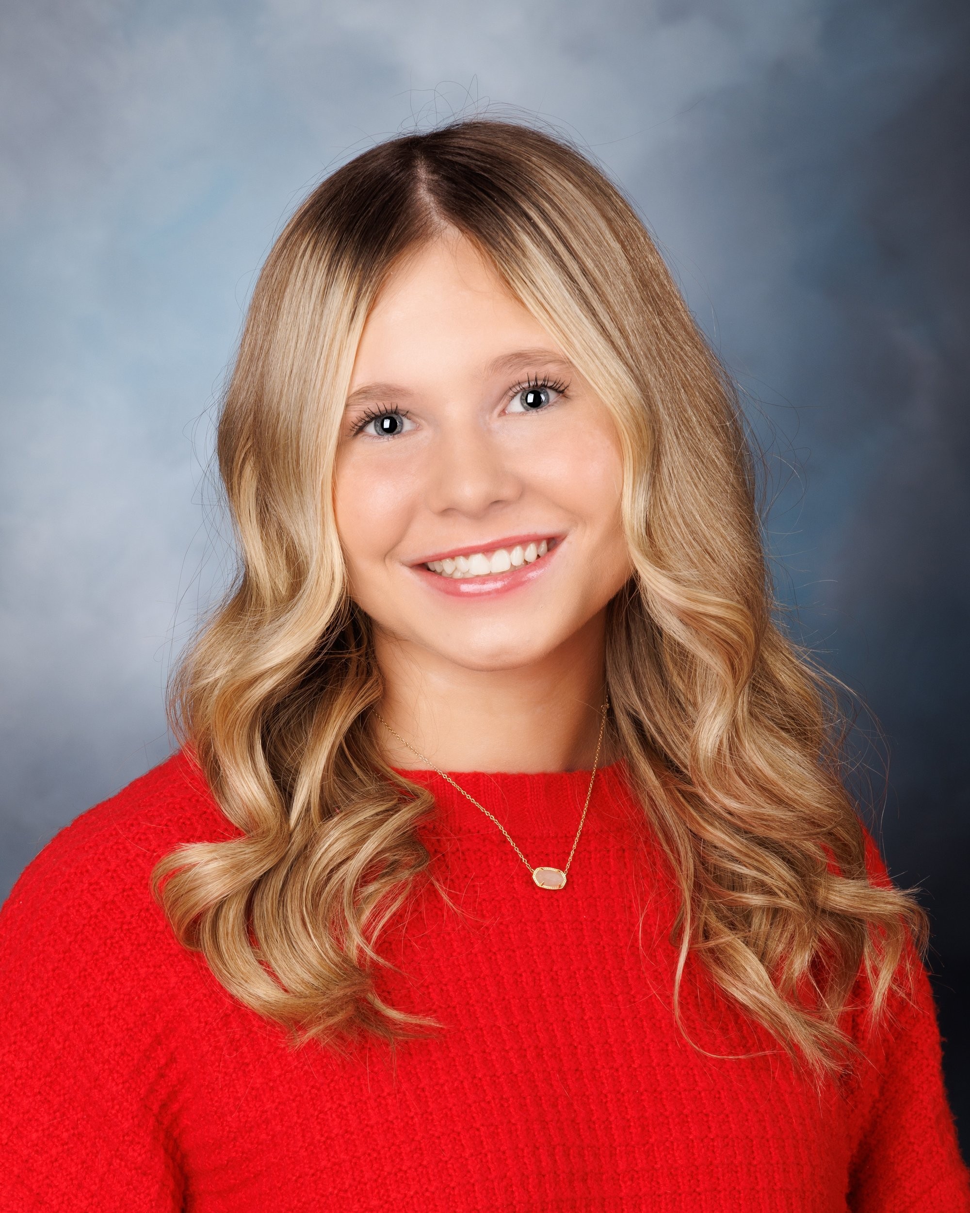 Trenton senior graduate McKenzie in a pink graduation gown with a 2023 tassel, smiling against a rustic backdrop