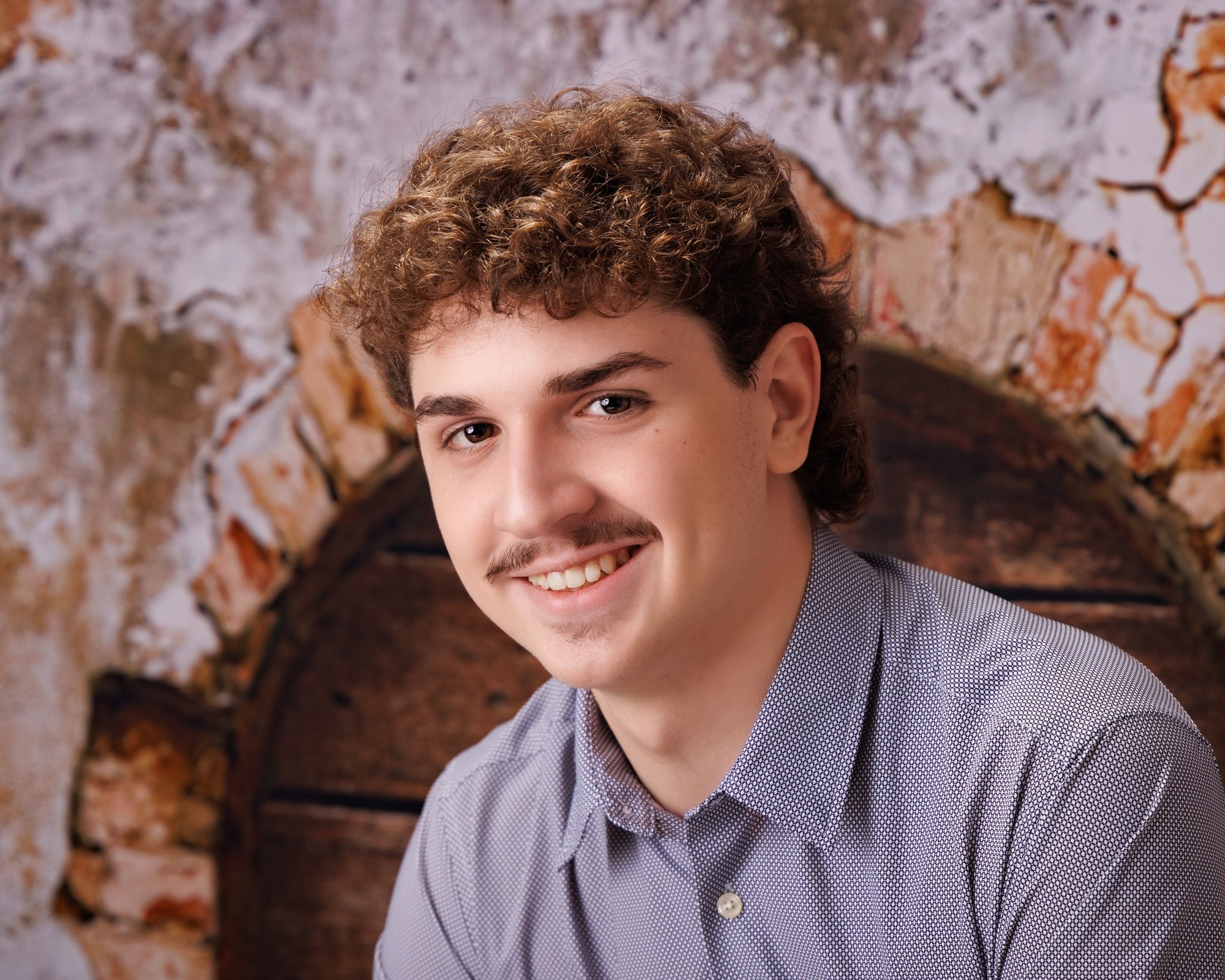 Michael’s confident senior photo with arms crossed against a textured brick background in a Downriver photography session