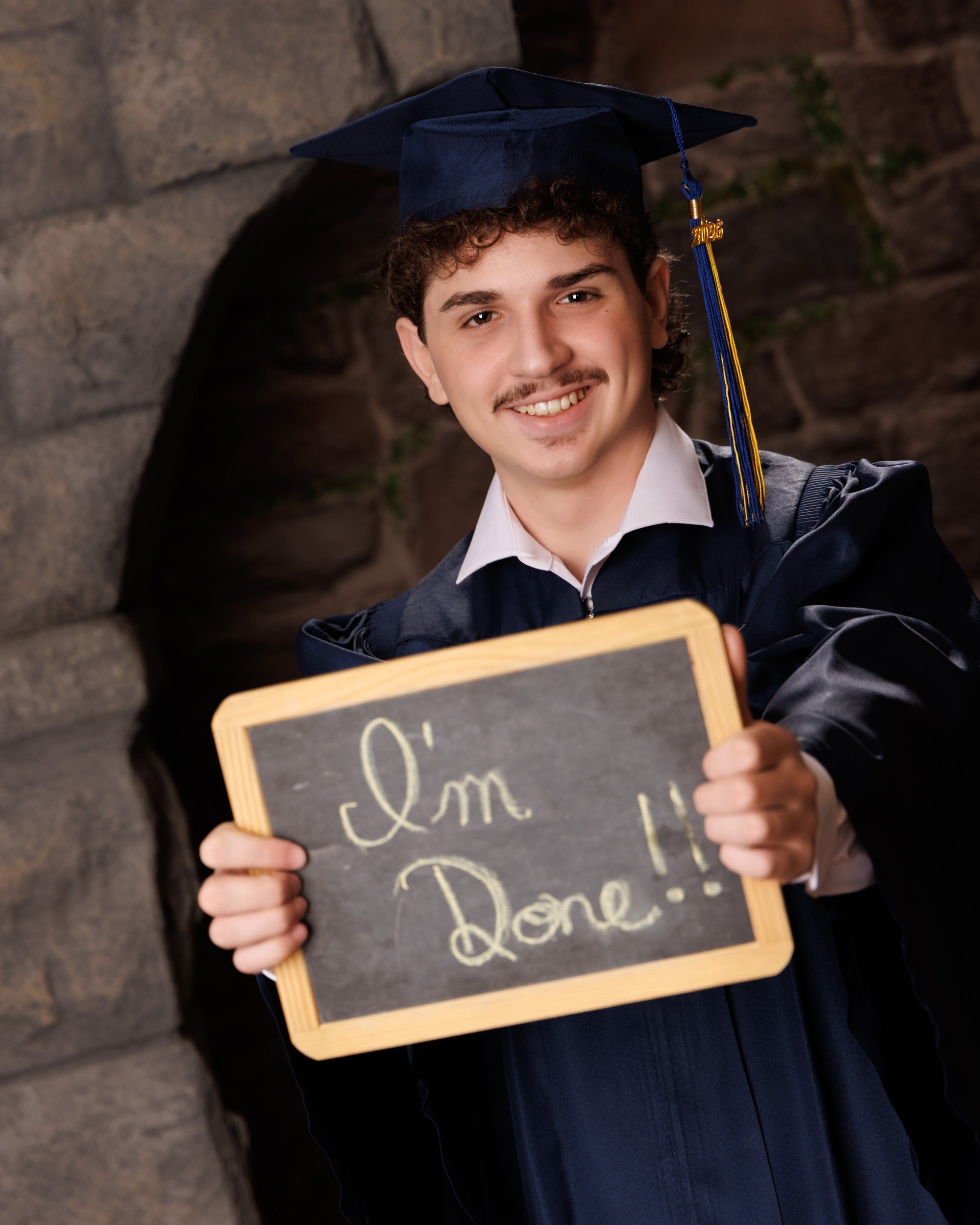 Trenton senior graduation celebration shot featuring Michael holding a 'I'm Done!' chalkboard and cap