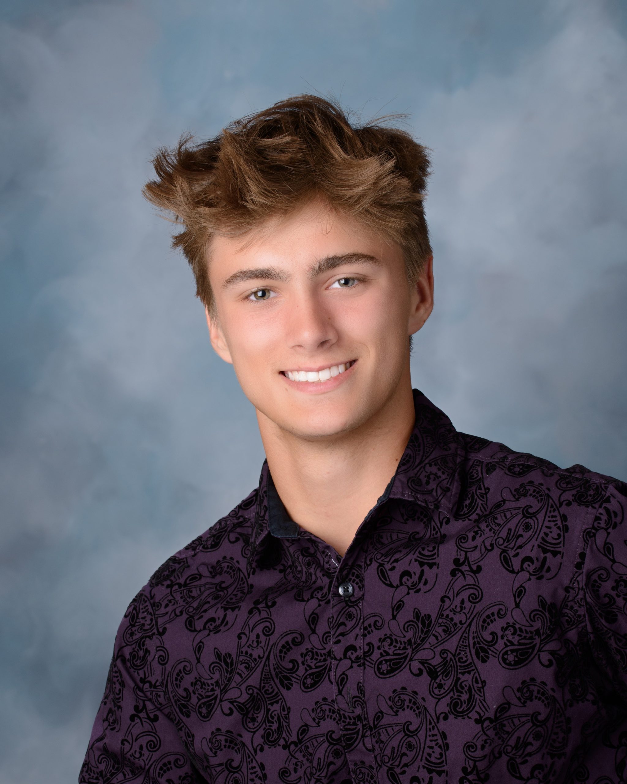 Trenton senior photo featuring a young man with styled hair in a purple paisley shirt against a soft blue studio backdrop