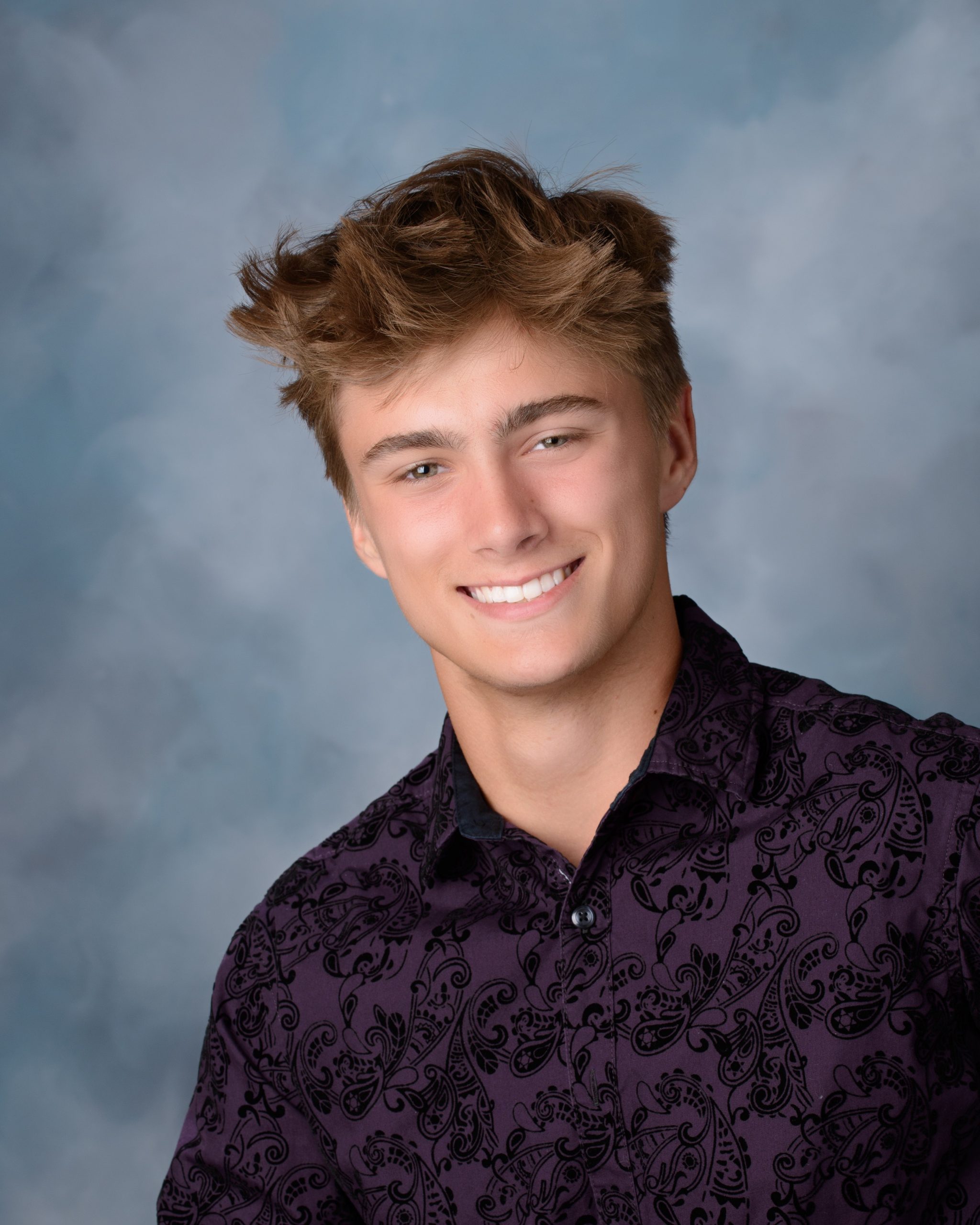 Professional headshot of a Trenton student wearing a purple patterned shirt with a dark background