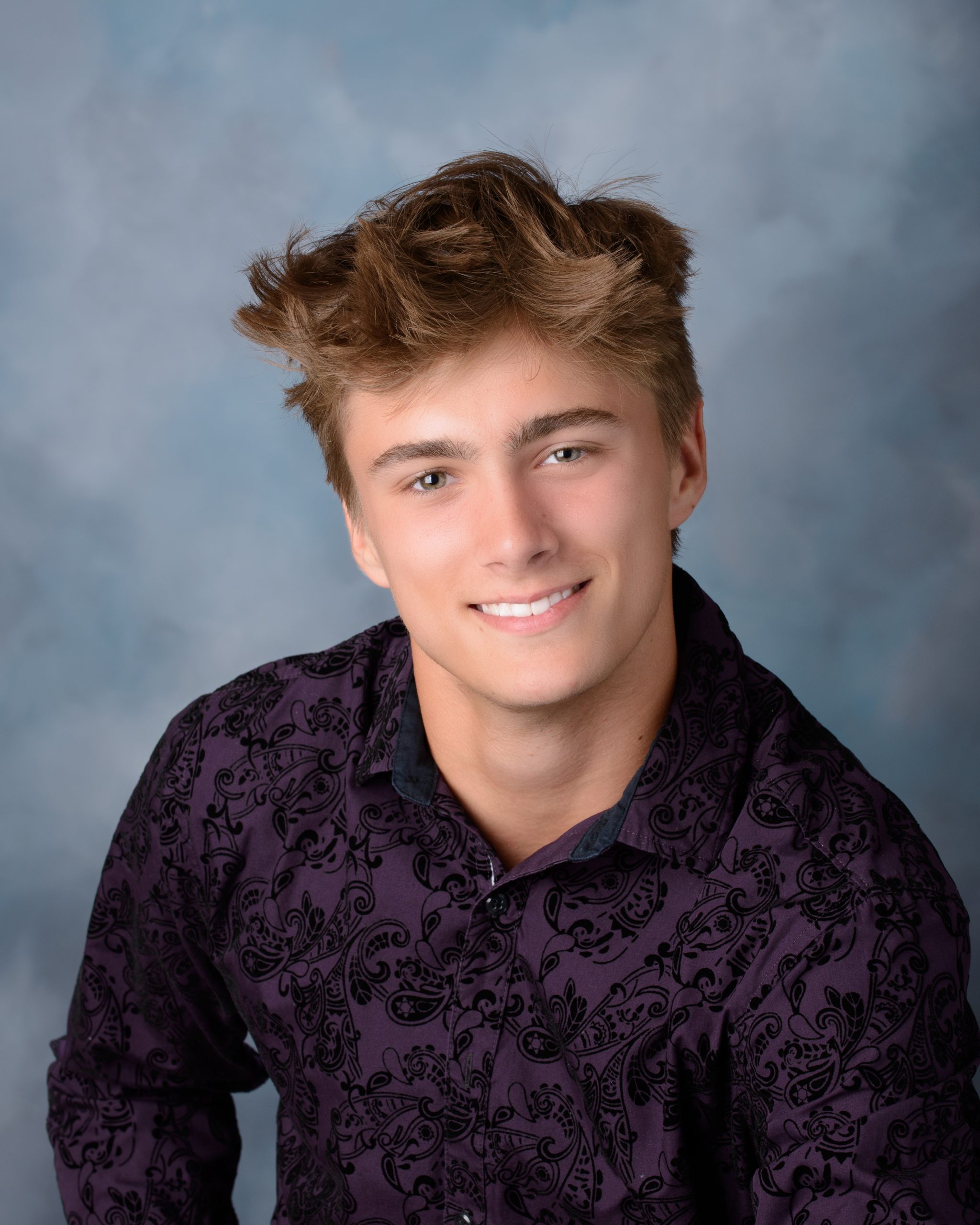 Casual Trenton senior session portrait showing a young man in layered clothing with a graffiti wall backdrop