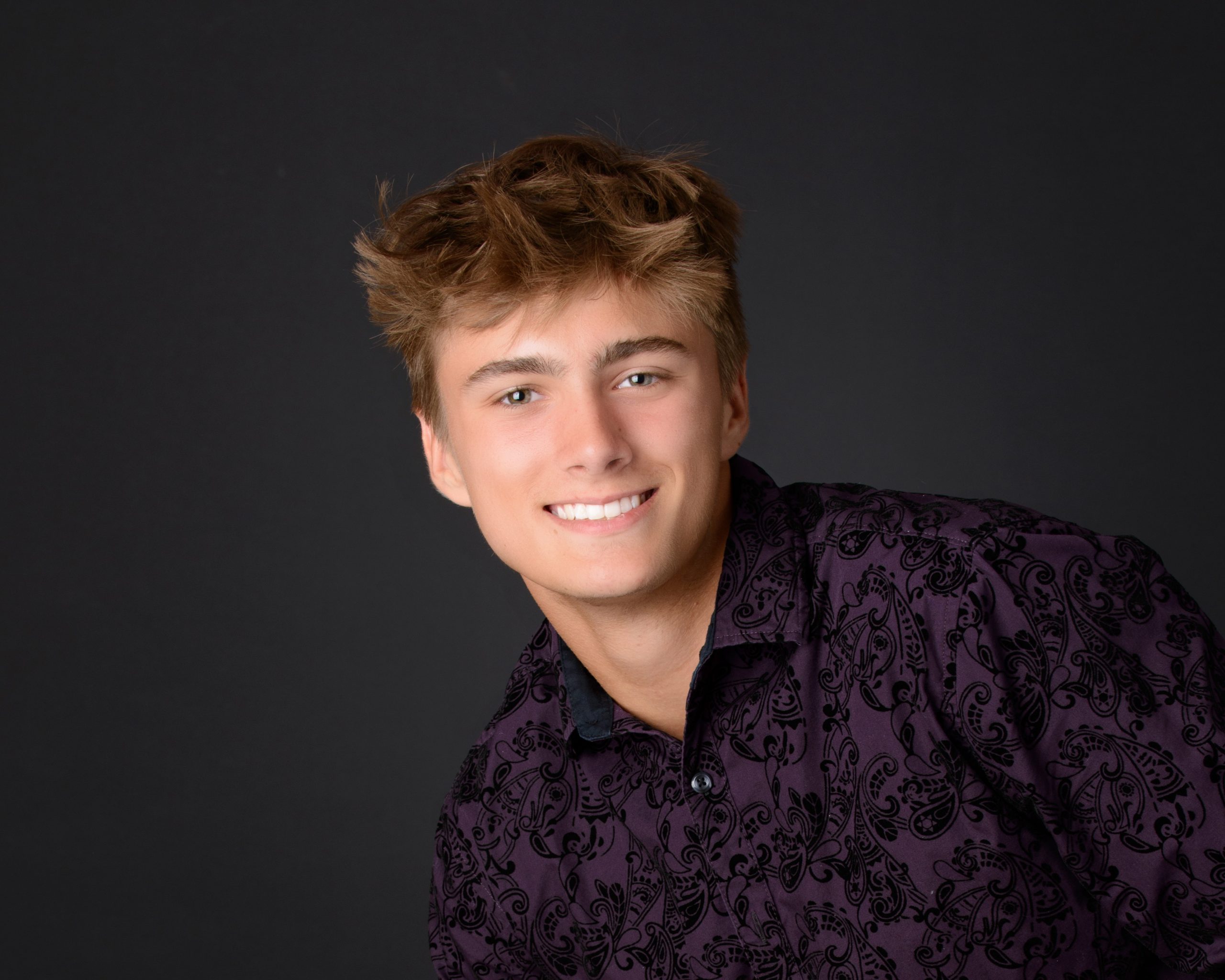 Casual Trenton senior session portrait showing a young man in layered clothing with a graffiti wall backdrop