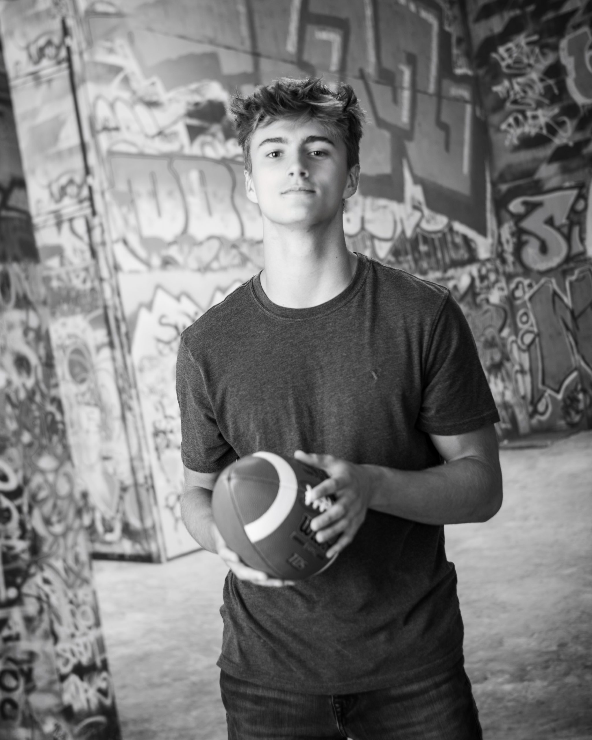 Casual Trenton senior session portrait showing a young man in layered clothing with a graffiti wall backdrop