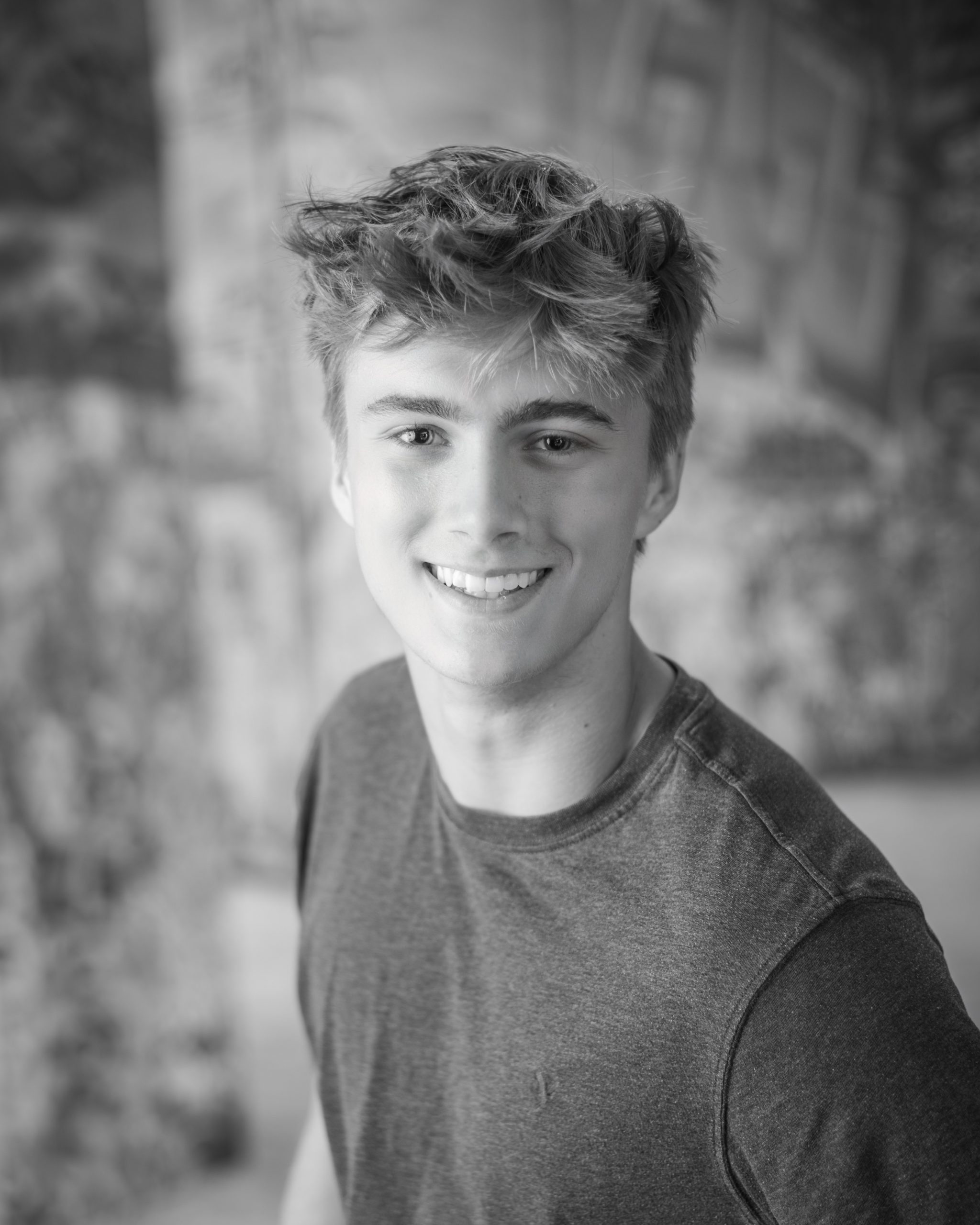 Casual Trenton senior session portrait showing a young man in layered clothing with a graffiti wall backdrop