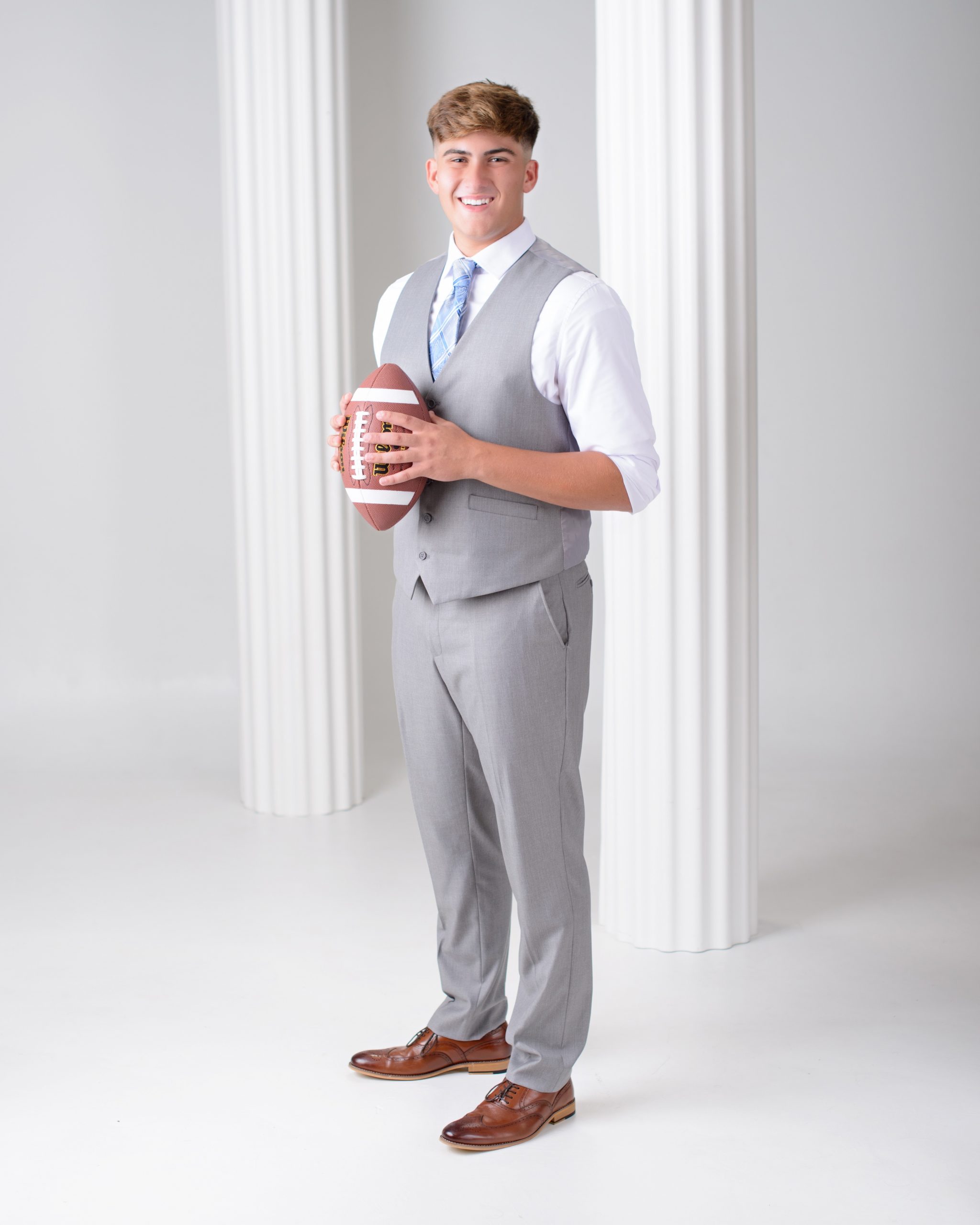 Student holding baseball in front of Trenton Trojans jerseys for high school senior photography