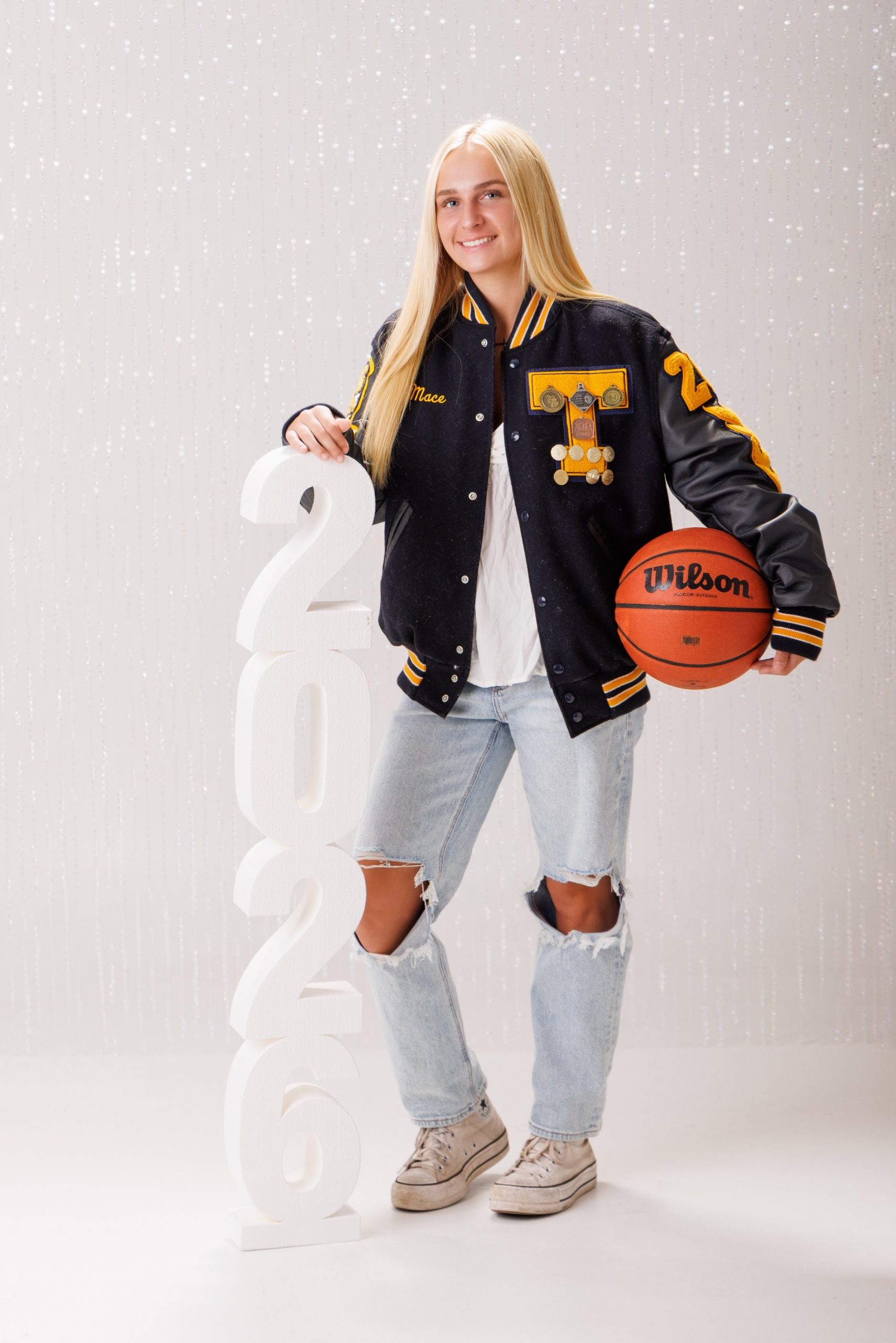 Back view of Alencia's Trenton Varsity jacket featuring 'Trenton' and 'Varsity' lettering with sports logos