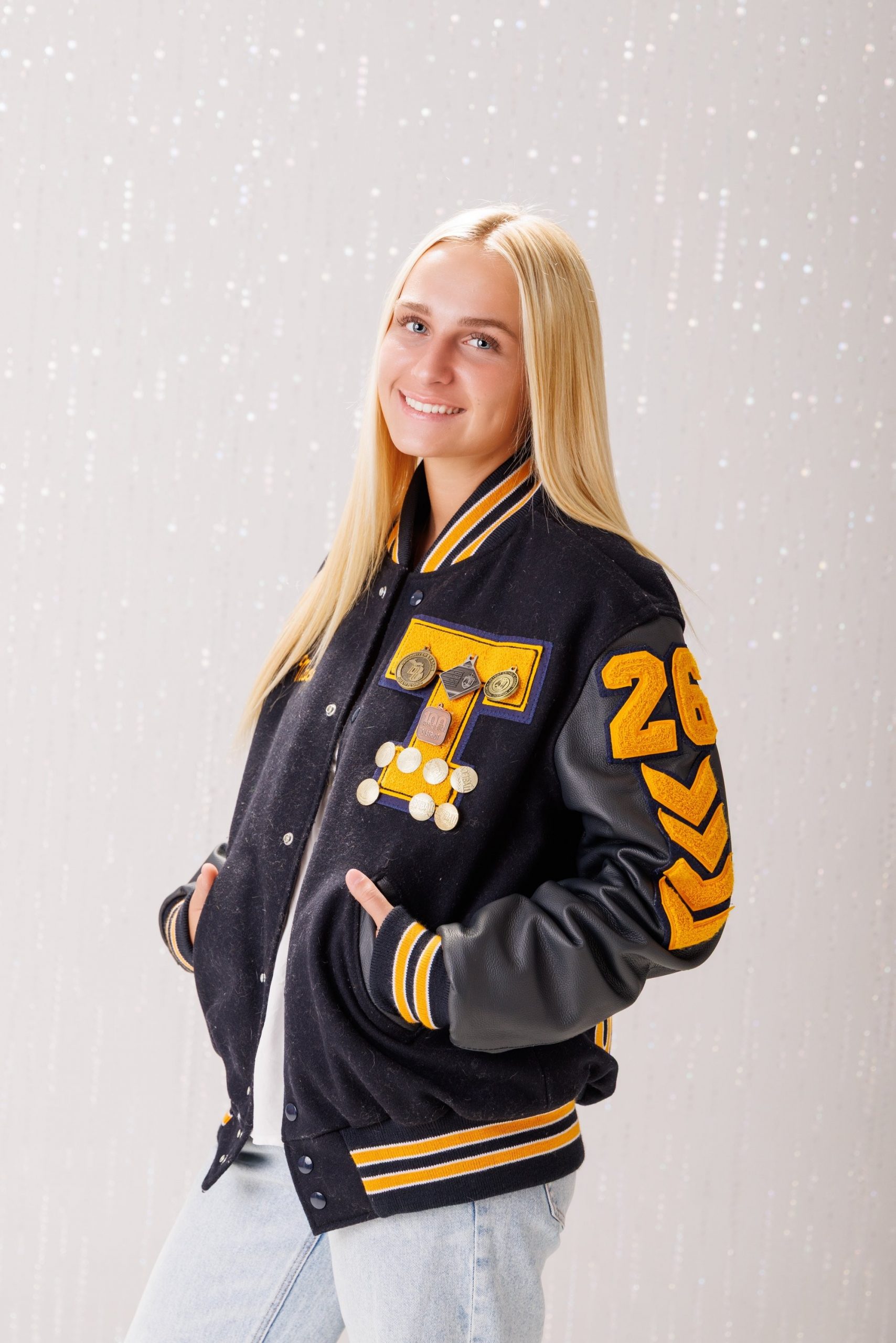 Back view of Alencia's Trenton Varsity jacket featuring 'Trenton' and 'Varsity' lettering with sports logos