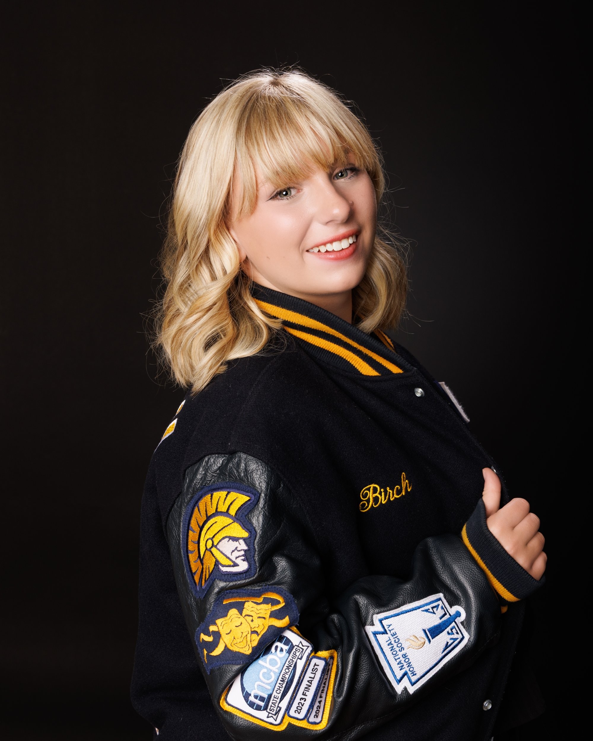 Student modeling a Trenton-themed varsity jacket with school name prominently displayed, posing confidently for senior photography.