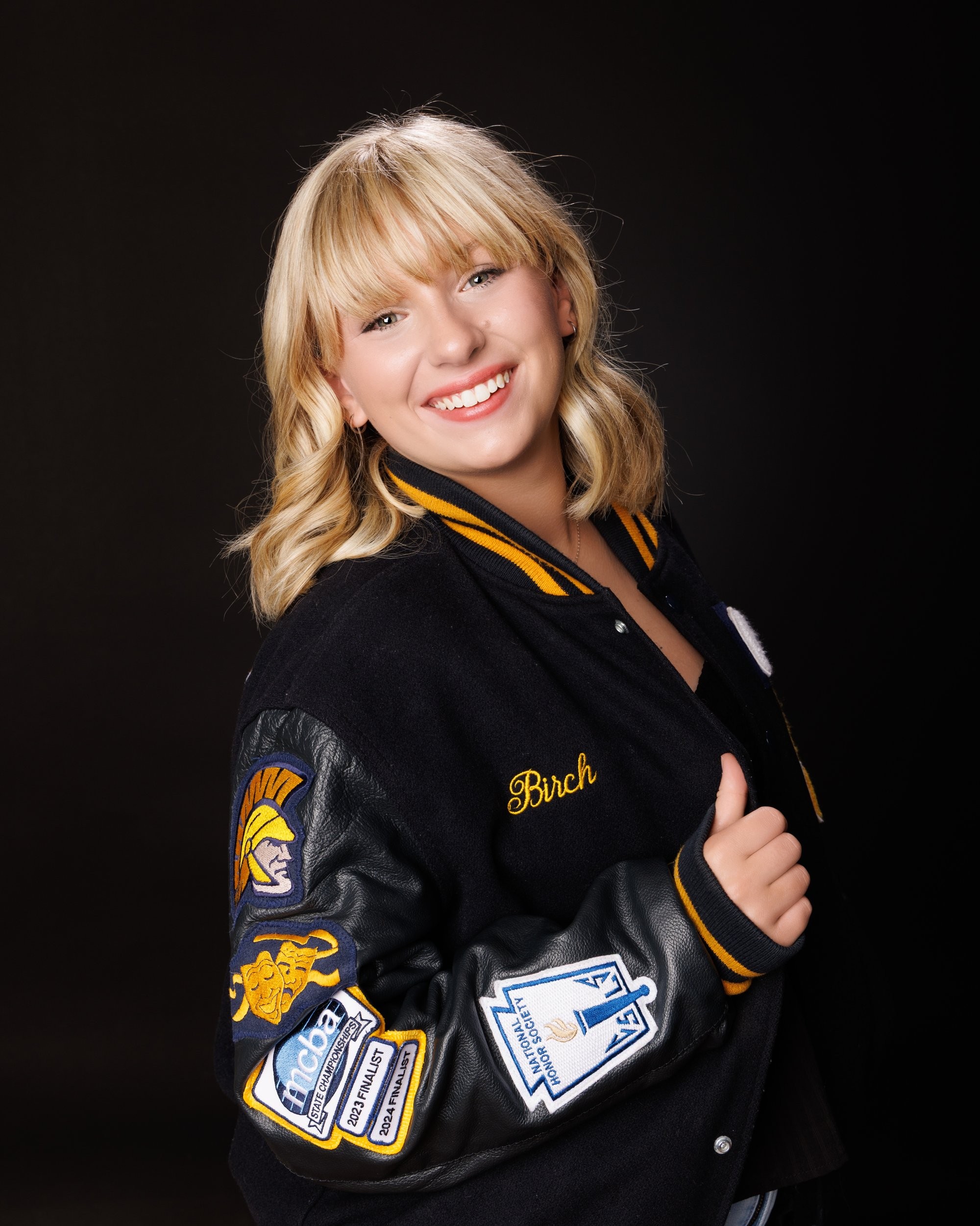 Student modeling a Trenton-themed varsity jacket with school name prominently displayed, posing confidently for senior photography.