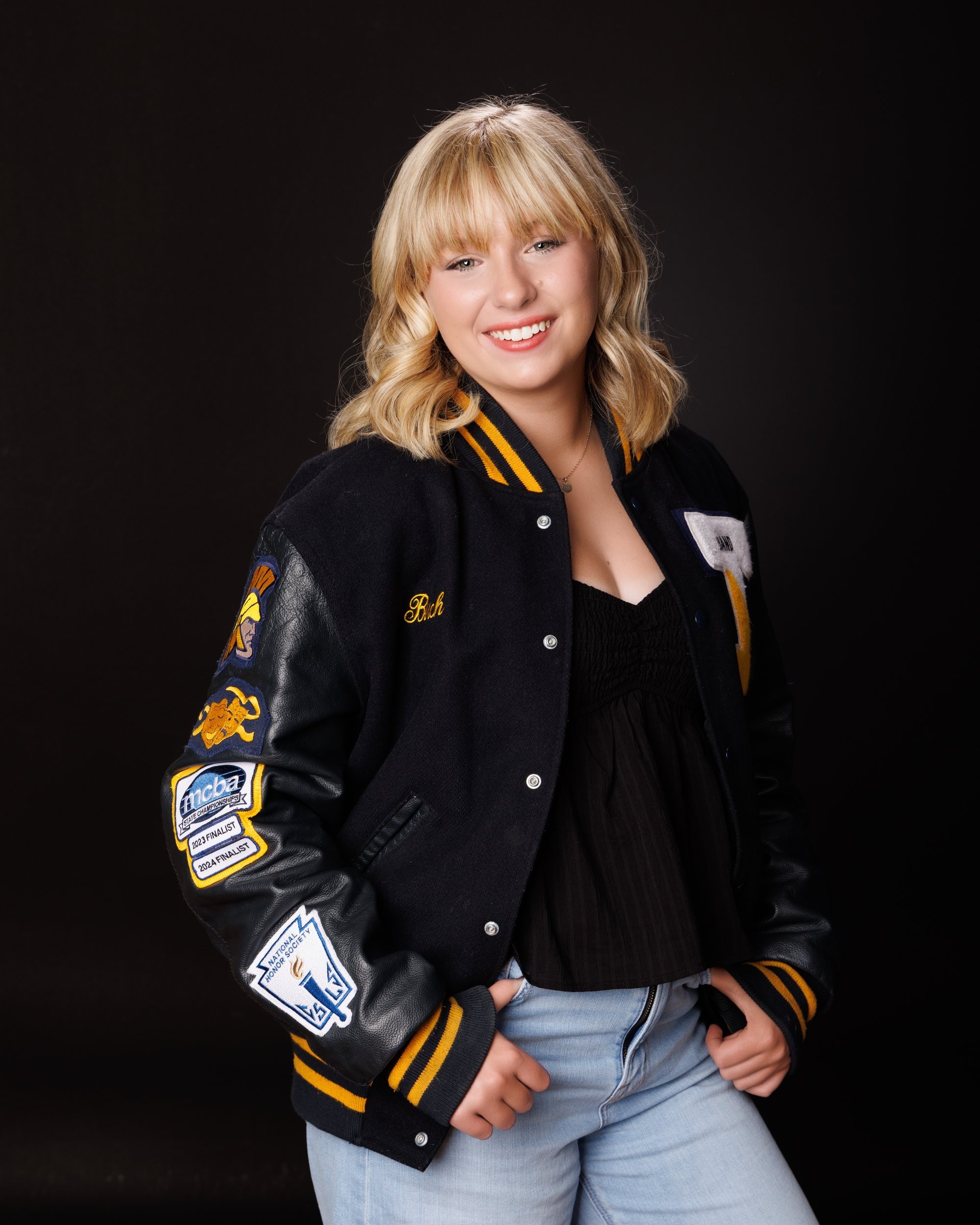 Student modeling a Trenton-themed varsity jacket with school name prominently displayed, posing confidently for senior photography.