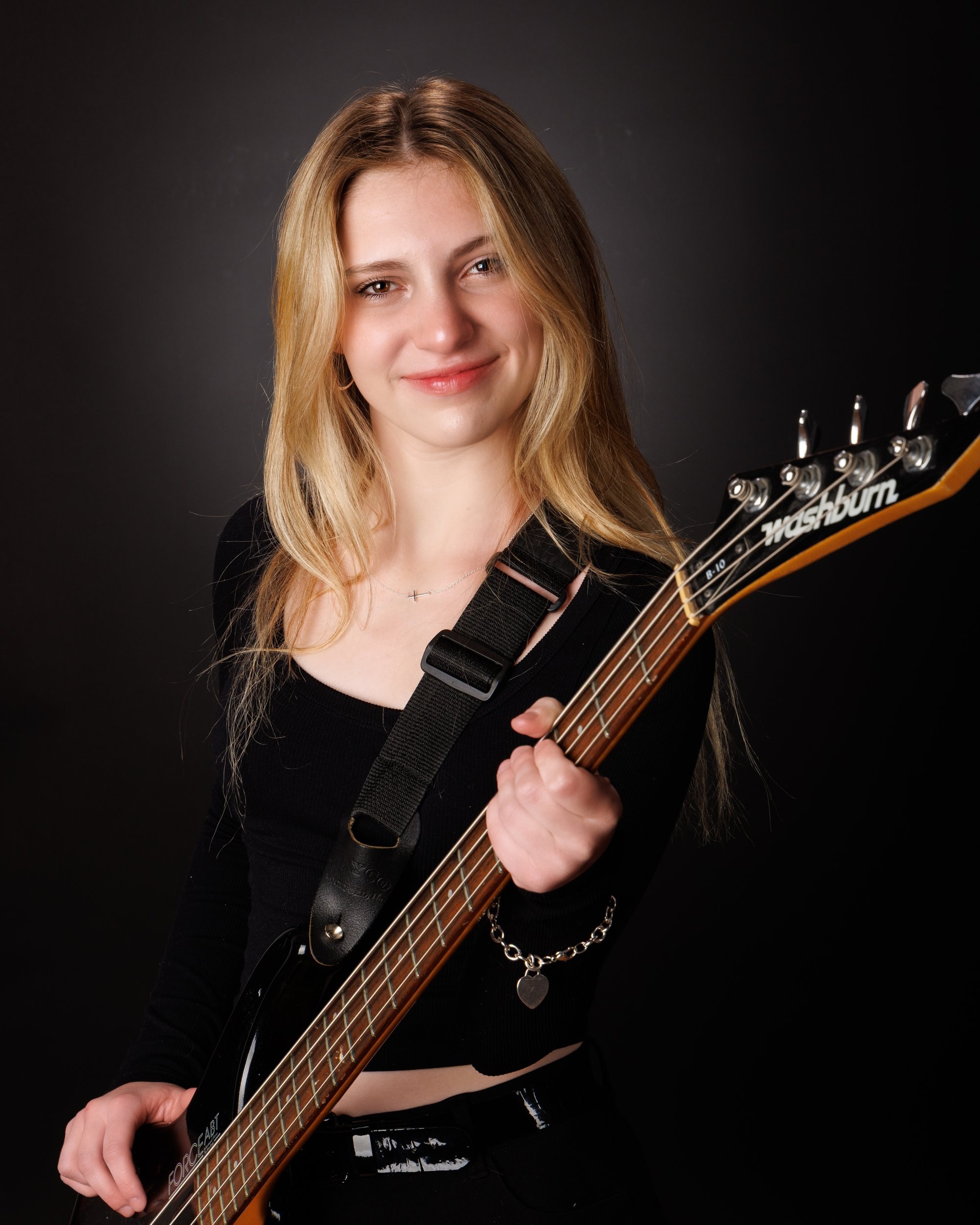 Senior portrait of Tegan holding a bass guitar, captured by a Trenton photo studio