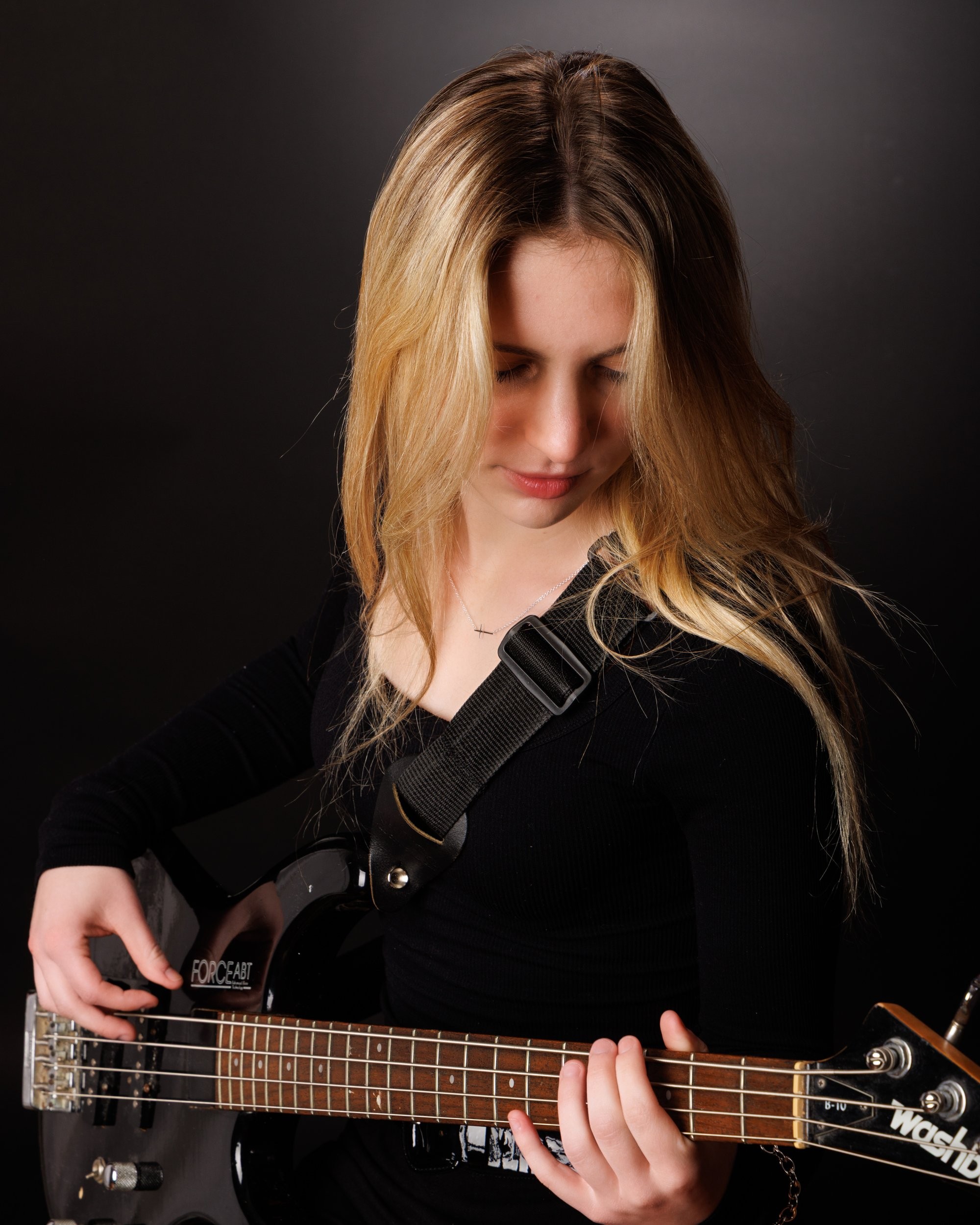Senior portrait of Tegan holding a bass guitar, captured by a Trenton photo studio