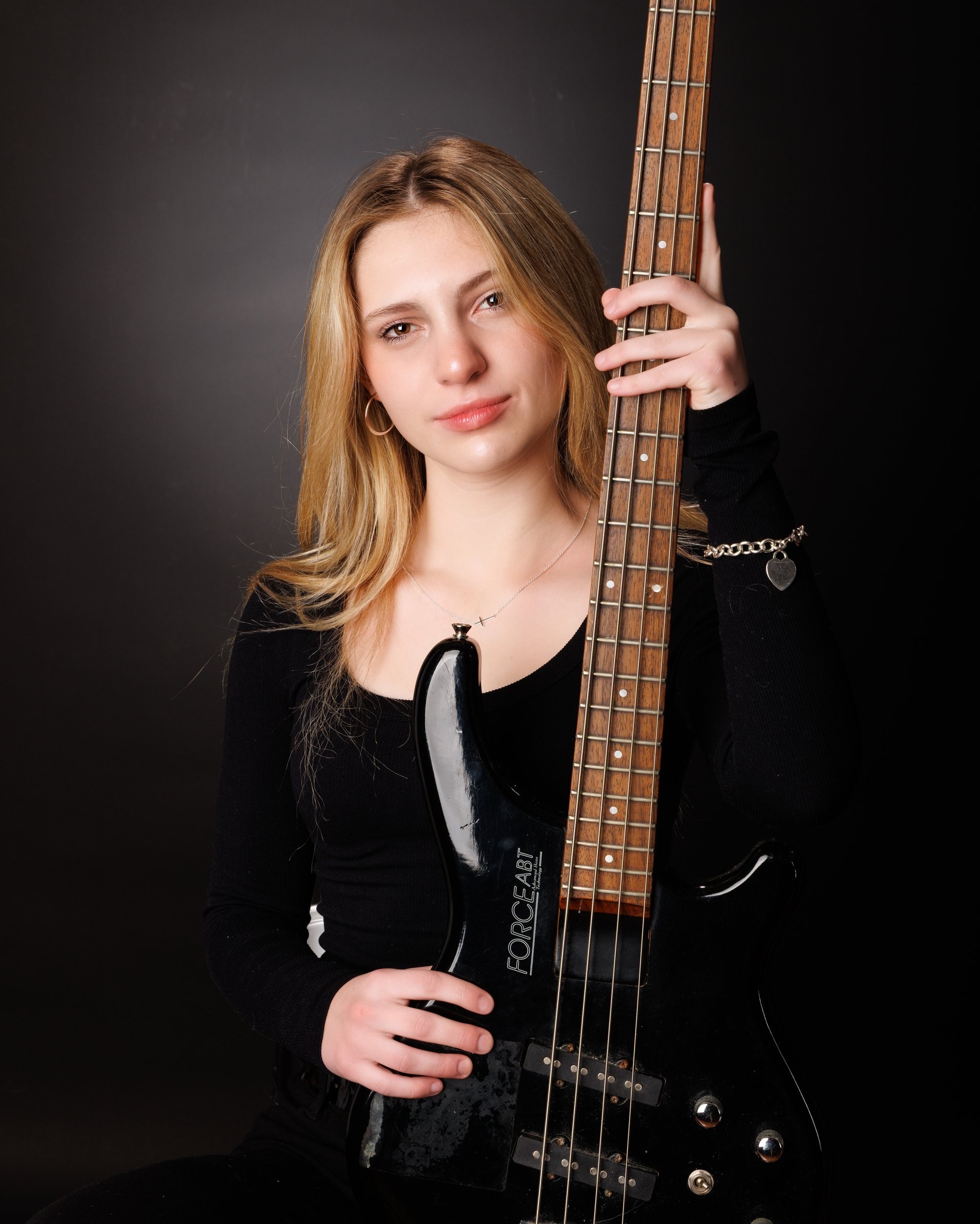 Senior portrait of Tegan holding a bass guitar, captured by a Trenton photo studio