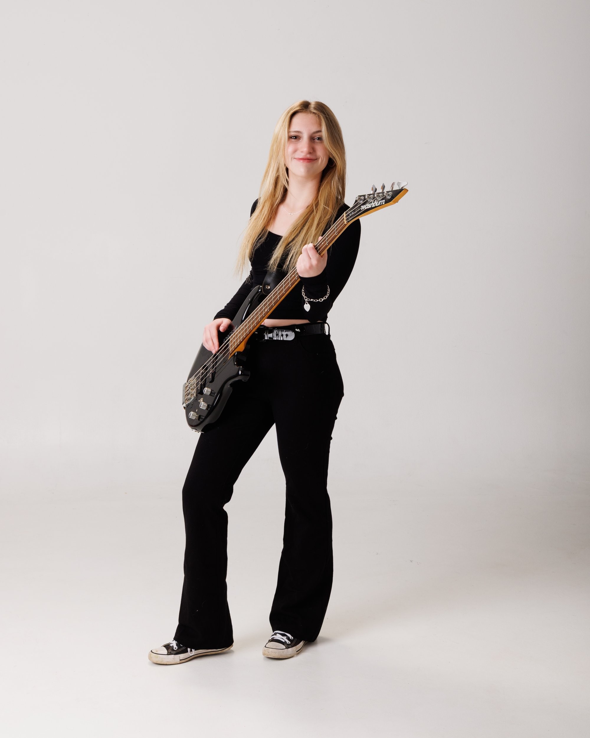 Senior portrait of Tegan holding a bass guitar, captured by a Trenton photo studio