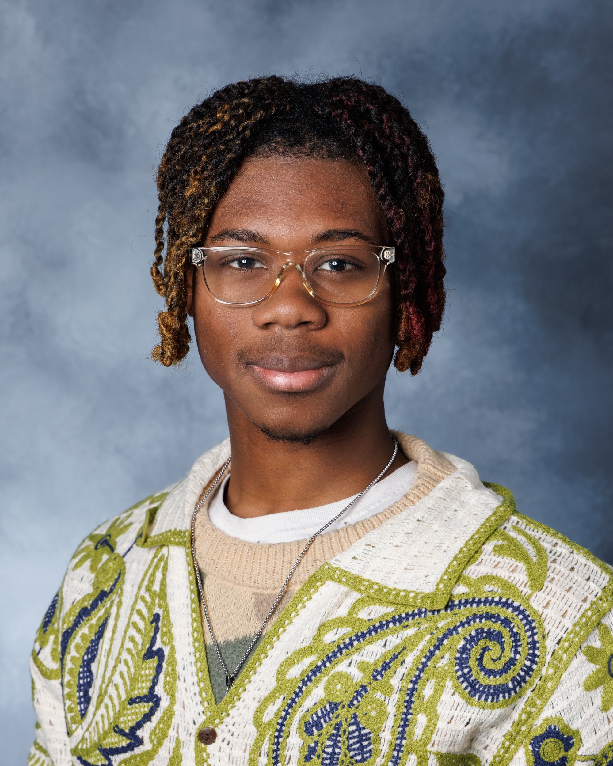 Young woman wearing glasses and white top seated in a blue studio setting