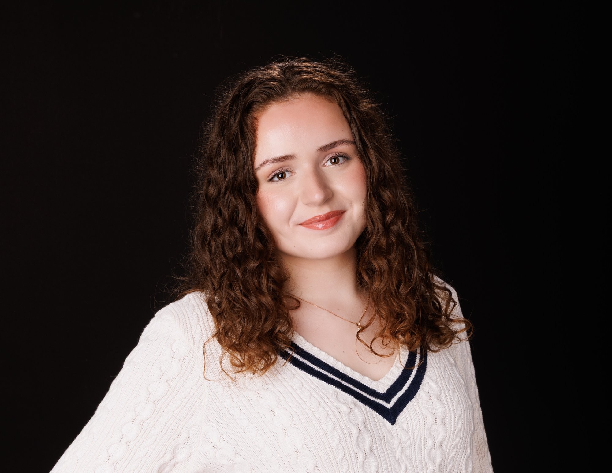 Viona's black studio senior photograph showcasing her curly hair and elegant sweater