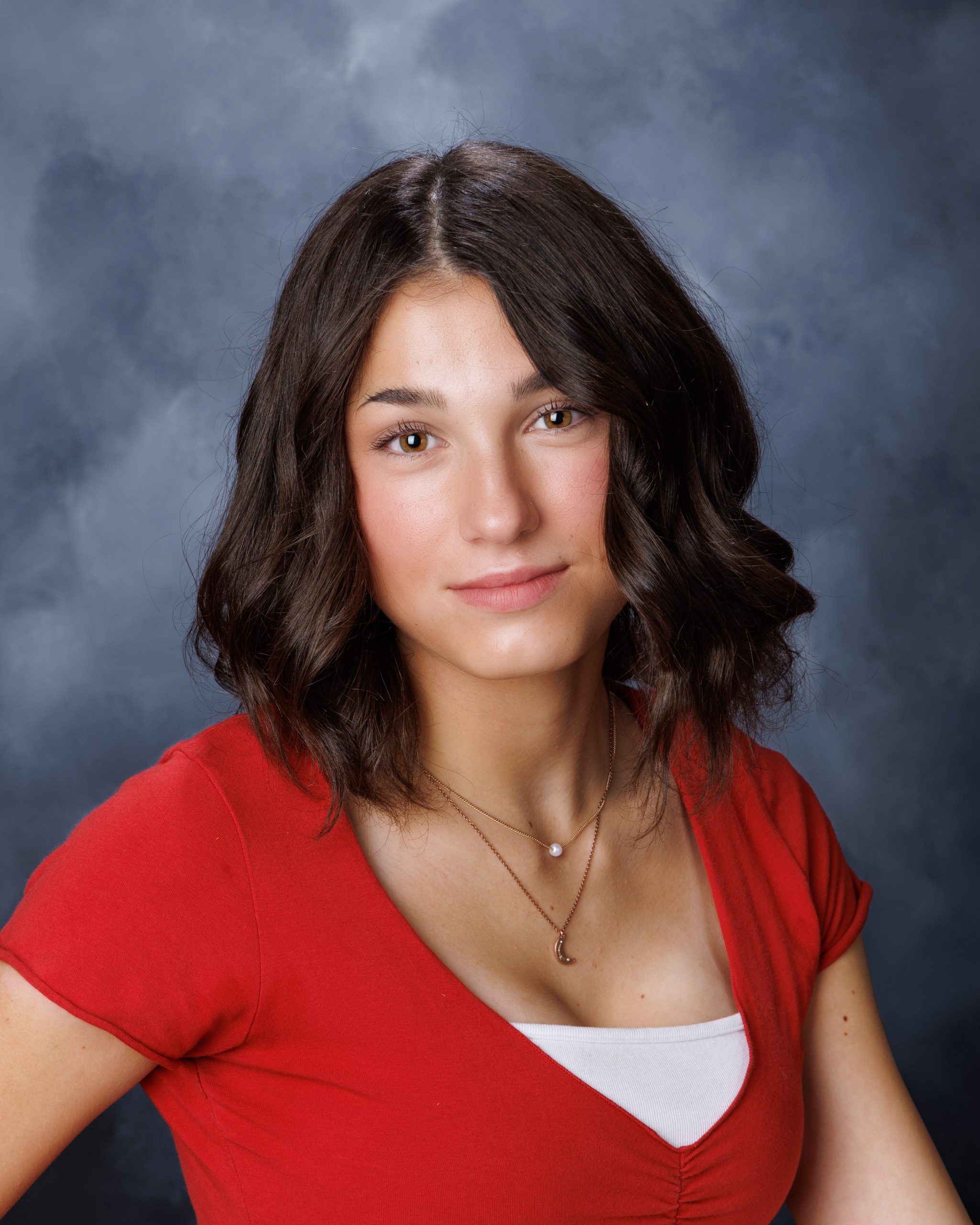 Anna wearing red top with floral garden backdrop during Woodhaven Senior Session