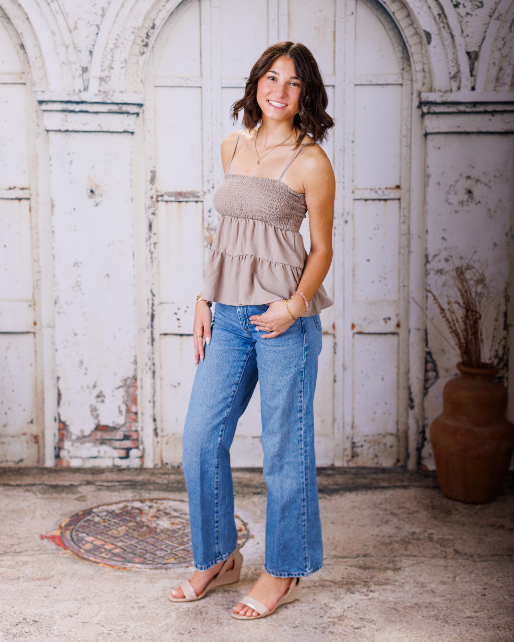 Anna posing in smocked peplum top with arched doorway backdrop at Woodhaven Senior Session