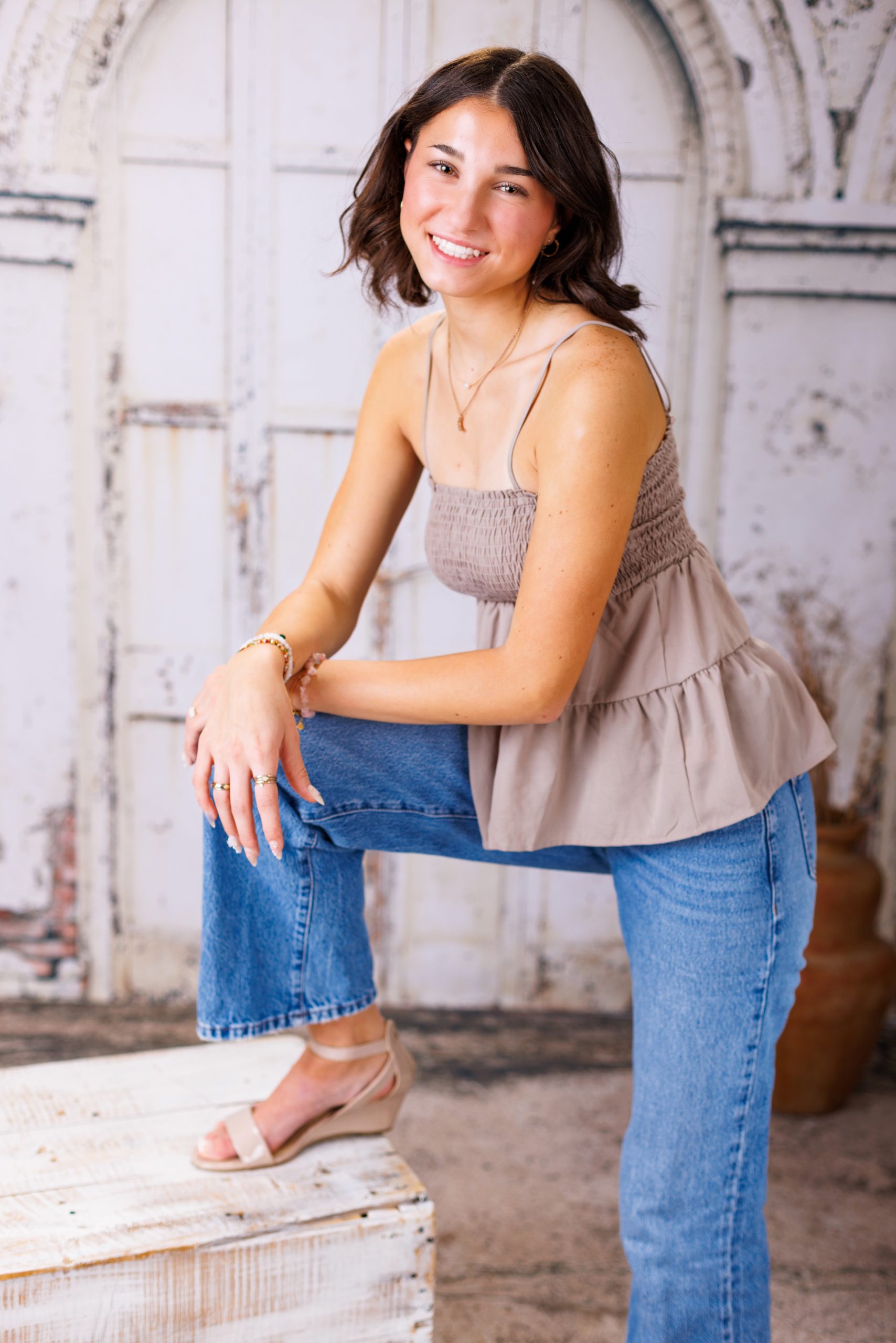 Anna posing in smocked peplum top with arched doorway backdrop at Woodhaven Senior Session